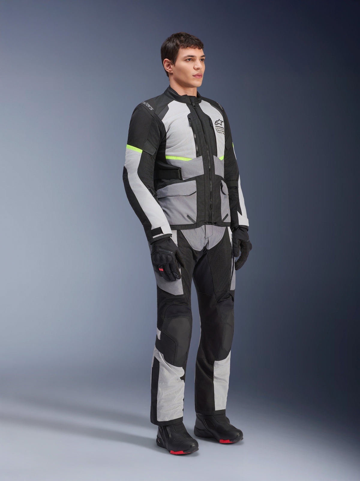 Alpinestars Andes Air Drystar® jakke og bukser, adventure touring motorcykeludstyr, isgrå, mørkegrå og sort med neongule detaljer, båret med sorte handsker og støvler, studieoptagelse i fuld figur til touring i to sæsoner.