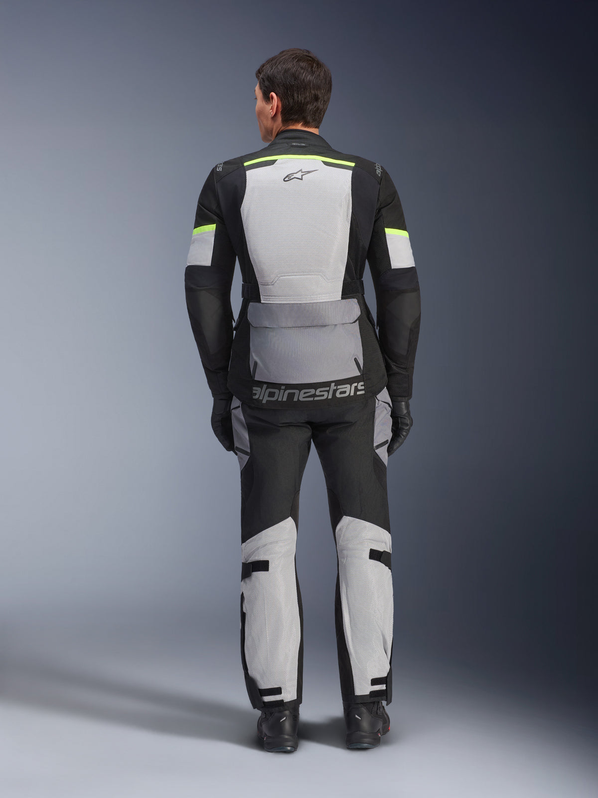 Alpinestars Andes Air Drystar® jakke og bukser, Ice Gray Dark Gray Black adventure touring-sæt, set bagfra af kører i komplet udstyr med neongule detaljer, med store mesh-ventilationspaneler og Alpinestars-branding.