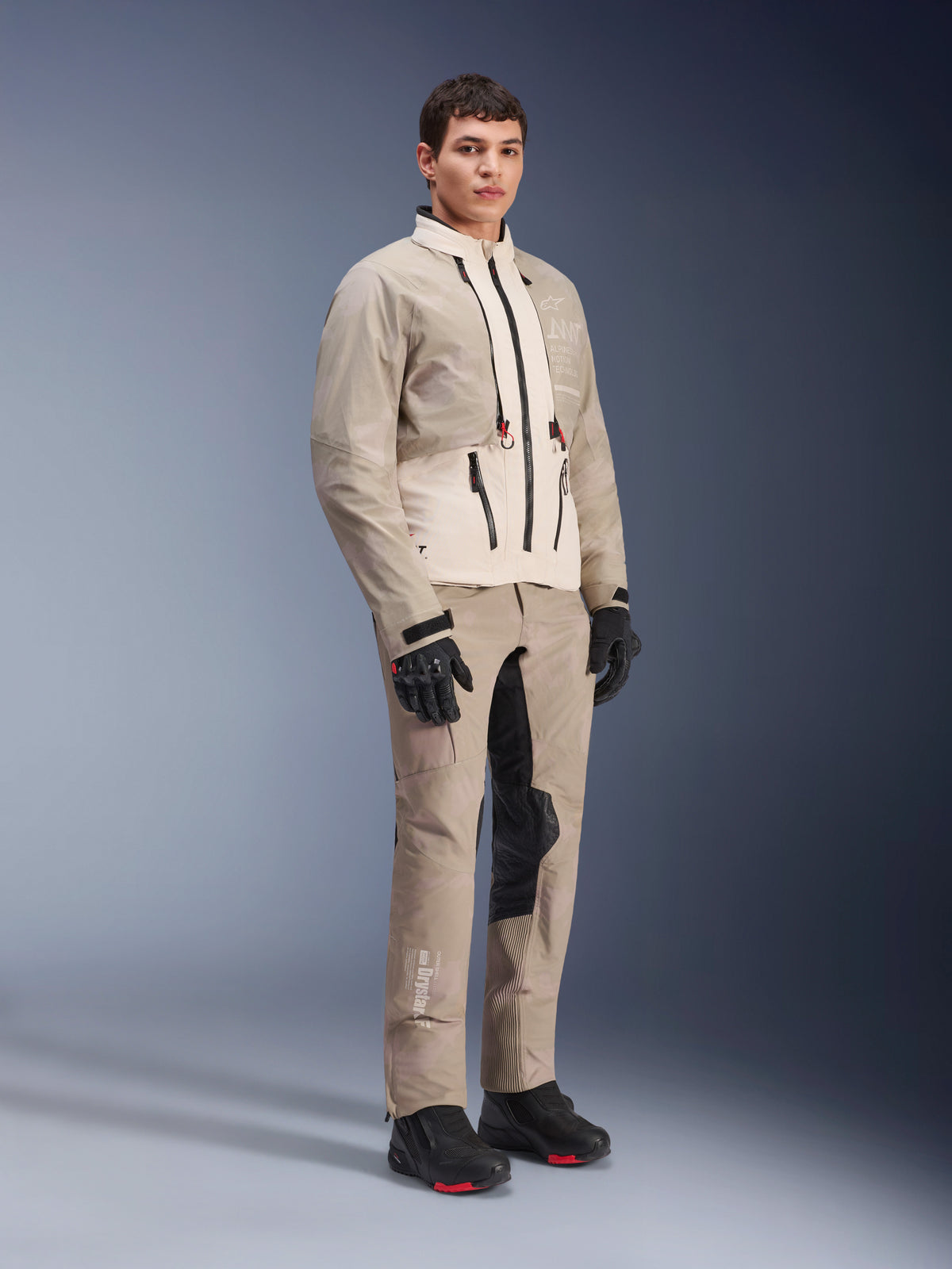 Alpinestars AMT-10LAB Drystar® XF-bukser og matchende jakke, Aluminum Camo adventure-køreudstyr, komplet outfit med sorte handsker og støvler, med teknisk branding og modulære beskyttelsespaneler, studio lifestyle-billede