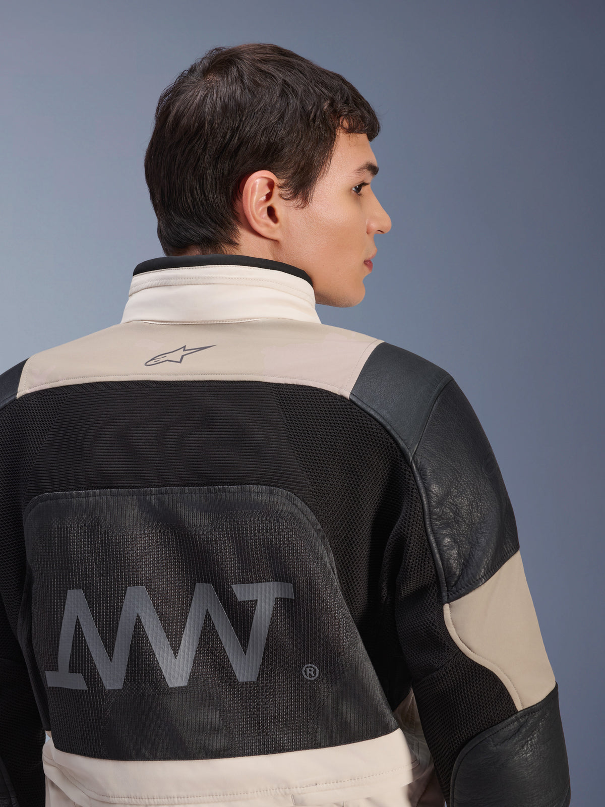 Alpinestars AMT-10LAB Drystar® XF Jacket, back view on male model, White Sand Aluminum Camo and black colorway, featuring large AMT branding, mesh ventilation panels, and leather reinforcements, technical adventure motorcycle apparel