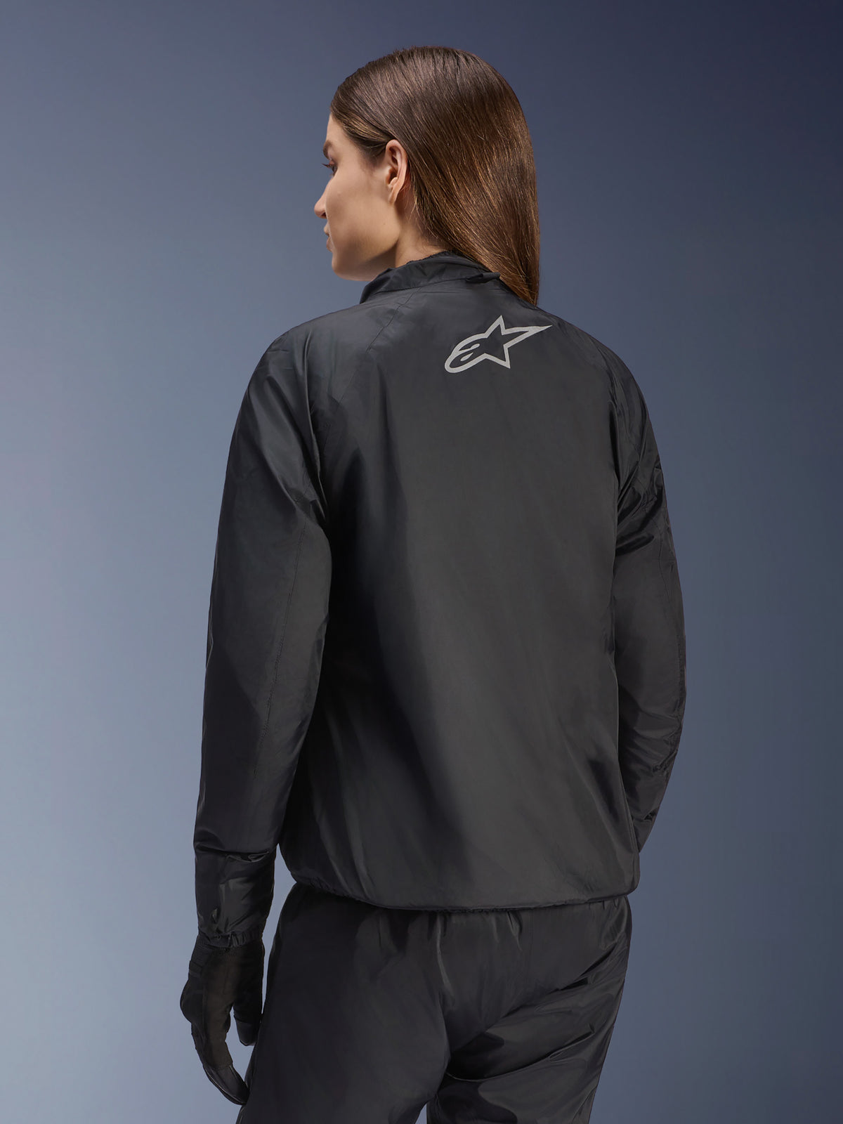 Alpinestars Stella Andes Air Drystar® jakke, motorcykeljakke til kvinder, sort, set bagfra med sølvfarvet stjernelogo, kombineret med sorte bukser og handsker, letvægts vandtæt touringudstyr