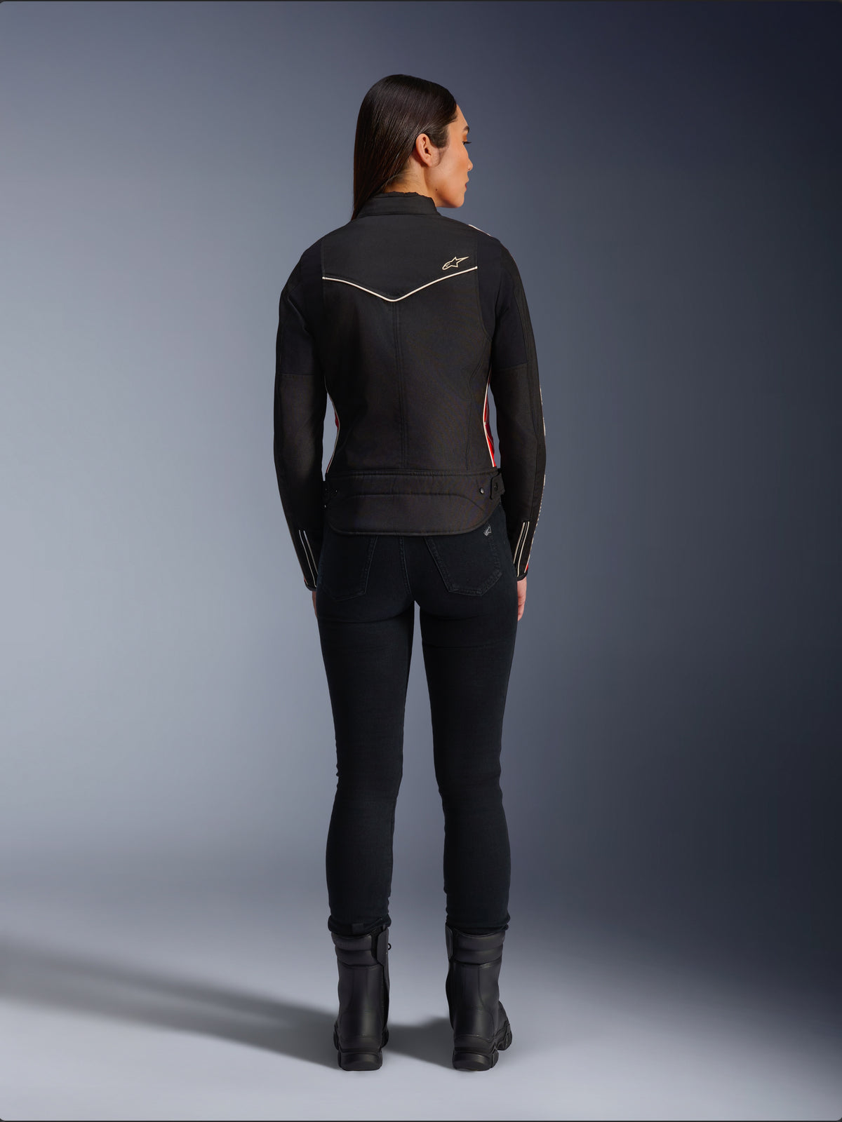 Alpinestars Stella T-Dyno WR-jakke i Black Bright Red Fuchsia, kvindelig model set bagfra, tekstil motorcykeljakke med kortere biker-pasform, hvidt stjernelogo på ryggen, stylet med sorte bukser og sorte støvler.