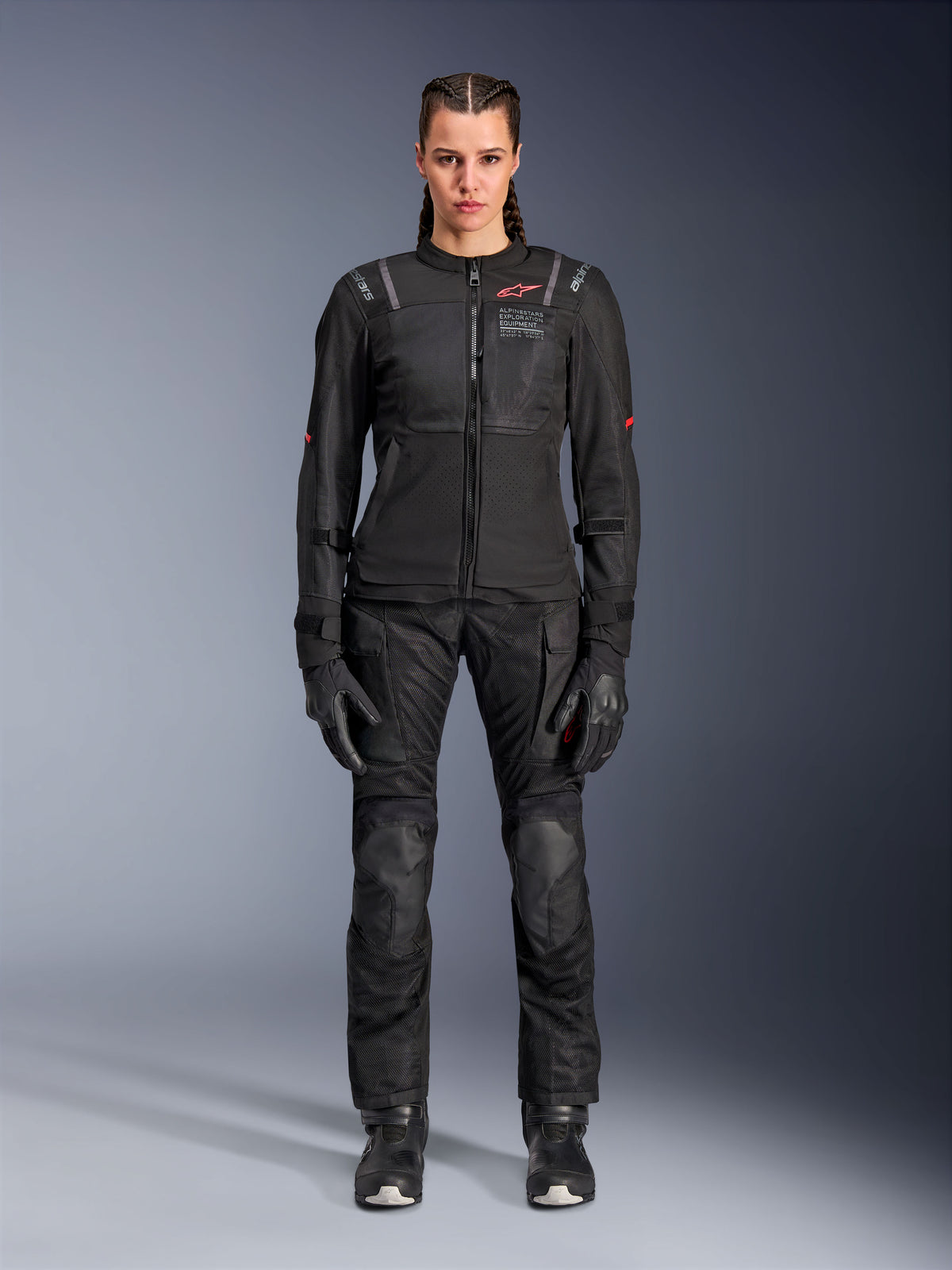 Alpinestars Stella ST-2 Air jakke, sort, fuldkropsstudiebillede af en kvindelig rytter iført matchende sorte motorcykelbukser og handsker, med high-flow mesh-paneler, røde logodetaljer og et moderne touring-design