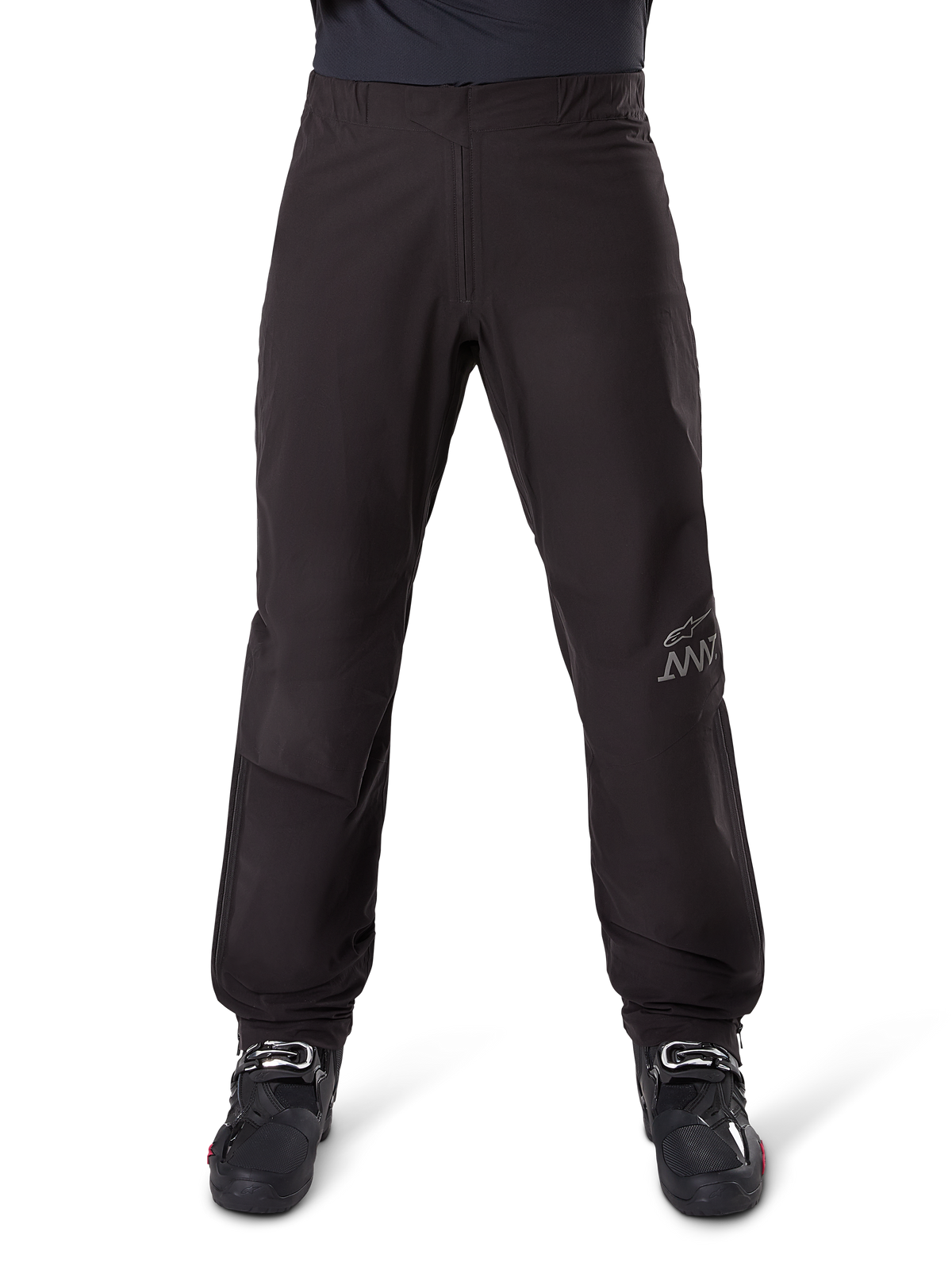 Alpinestars AMT-8 Stretch Drystar® XF bukseliner, sort, set forfra båret med sorte motorcykelstøvler, med gråt stjernelogo og AMT-branding på benet, alsidigt vandtæt og vindtæt motorcykeltøj