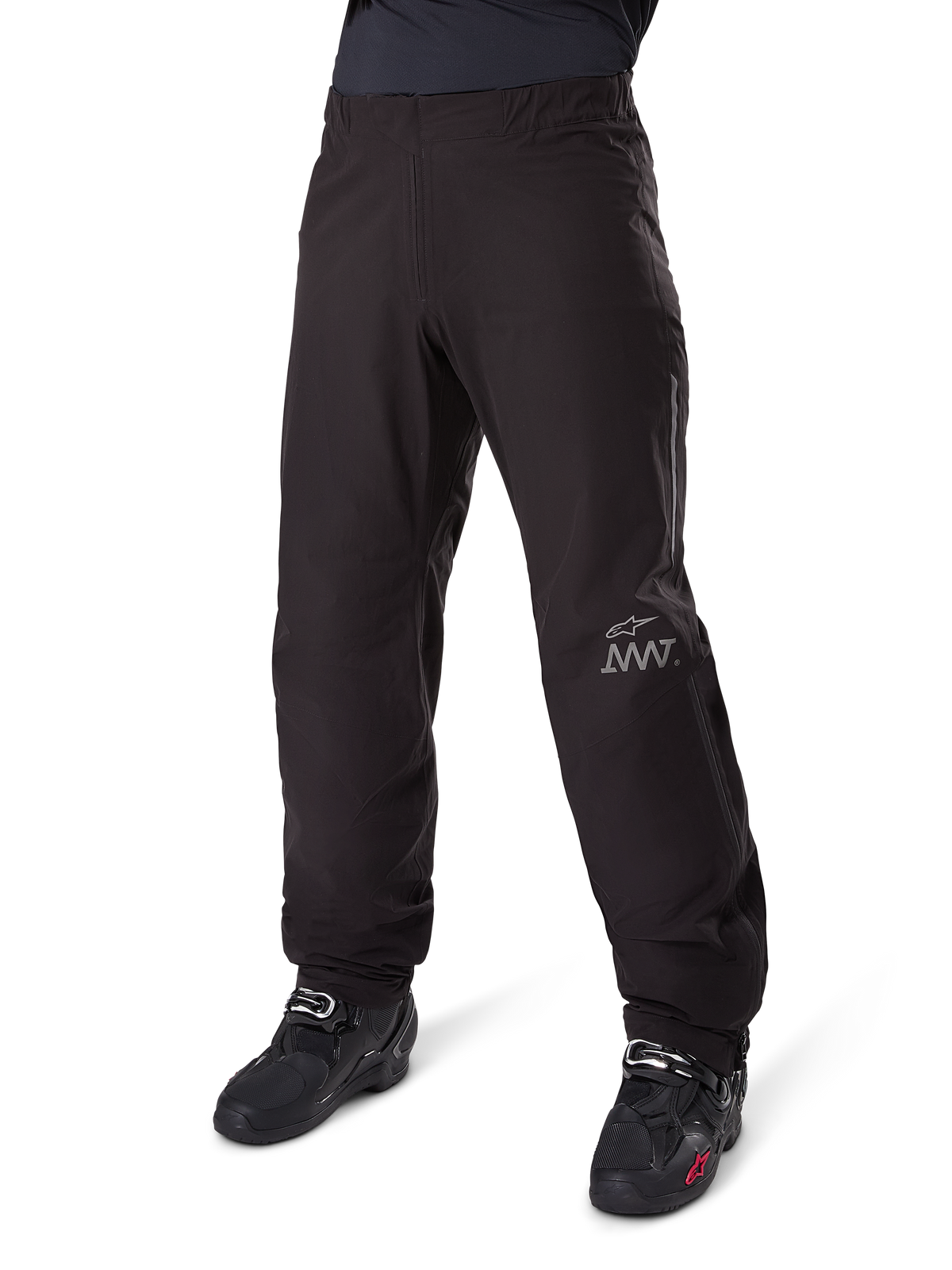 Alpinestars Amt-8 Stretch Drystar® XF bukse-liner, sort, vandtæt og strækbar tekstilkonstruktion med sølvfarvet AMT-logo, båret med sorte motorcykelstøvler, adventure touring motorcykeludstyr