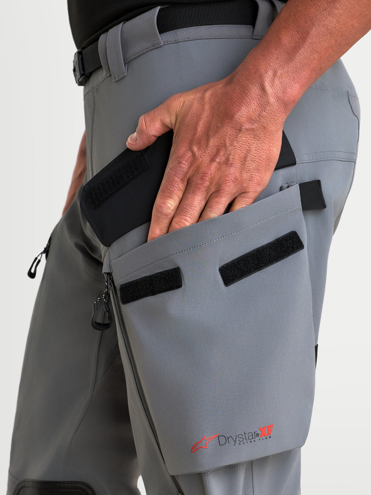 Alpinestars Maxdura Drystar XF Laminated Pants, Dark Gray and Black adventure motorcycle pants, featuring a hand accessing the angled thigh cargo pocket with Drystar XF branding