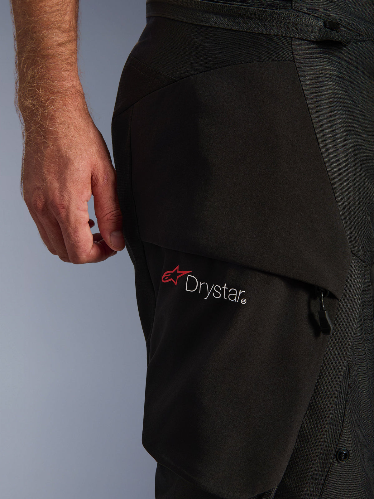 Alpinestars Andes V4 Drystar® bukser, detalje af en sort cargolomme med det hvide Drystar-logo og den røde stjerne, der viser den holdbare tekstilkonstruktion og lynlåsdetaljer.