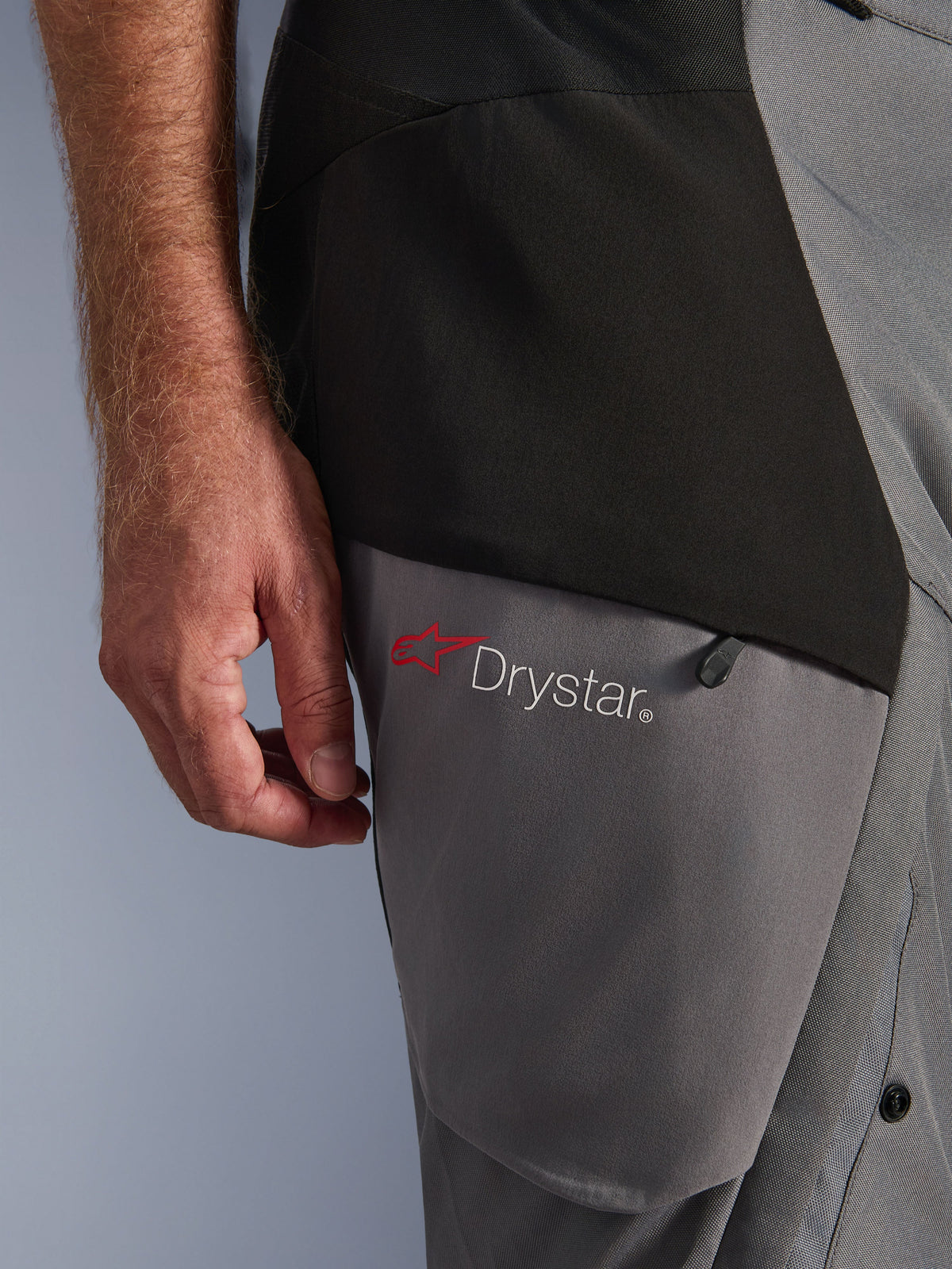 Alpinestars Andes V4 Drystar® bukser, sort mørkegrå, tætbillede af lårdetalje med rødt stjernelogo og Drystar® branding, holdbar tekstilkonstruktion med lynlåslomme, adventure køreudstyr