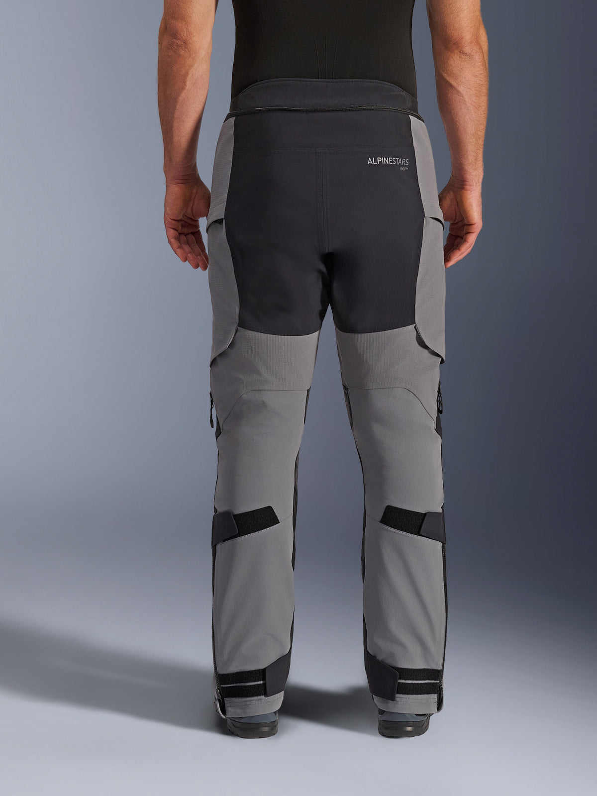Alpinestars Andes Pro Drystar® XF bukser, set bagfra, mørkegrå og sort, adventure motorcykelbukser med sorte forstærkede paneler på sædet, Alpinestars-logo bagpå og justerbare stropper bag knæene og ved anklerne for en sikker pasform.