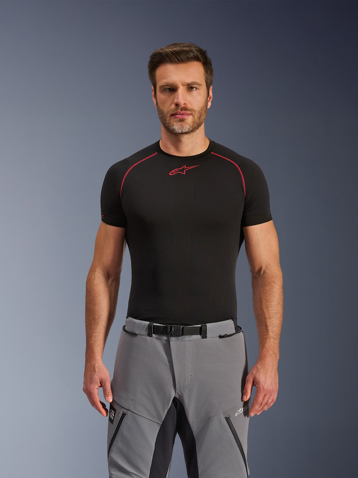 Alpinestars Andes Pro Drystar® XF bukser, adventure motorcykelbukser, mørkegrå og sort, båret af en mandlig model med et sort teknisk basislag, med magnetisk spænde i taljen, slidstærk tekstilkonstruktion og Drystar® XF branding til touring i al slags vejr