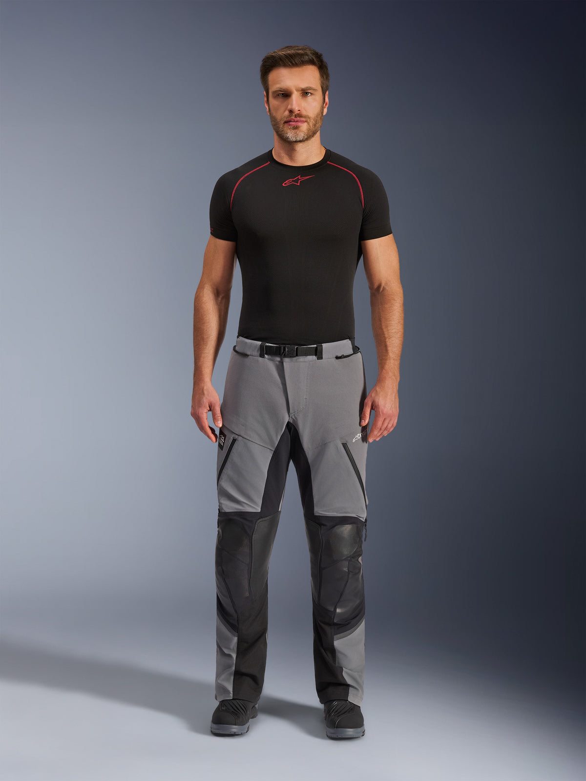 Alpinestars Andes Pro Drystar® XF bukser, adventure-motorcykelbukser, mørkegrå og sort, set forfra, båret af en model med et sort baselayer, med forstærkede knæpaneler og vandtætte lynlåslommer.