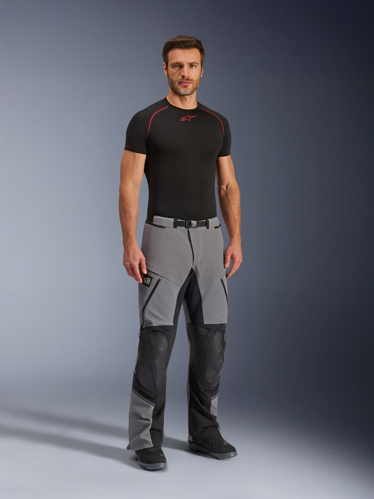 Alpinestars Andes Pro Drystar® XF bukser, motorcykel adventure-bukser, mørkegrå og sort, båret af en model med et sort teknisk basislag, multi-panel konstruktion med vandtætte lynlåse og forstærkede zoner til adventure-kørsel