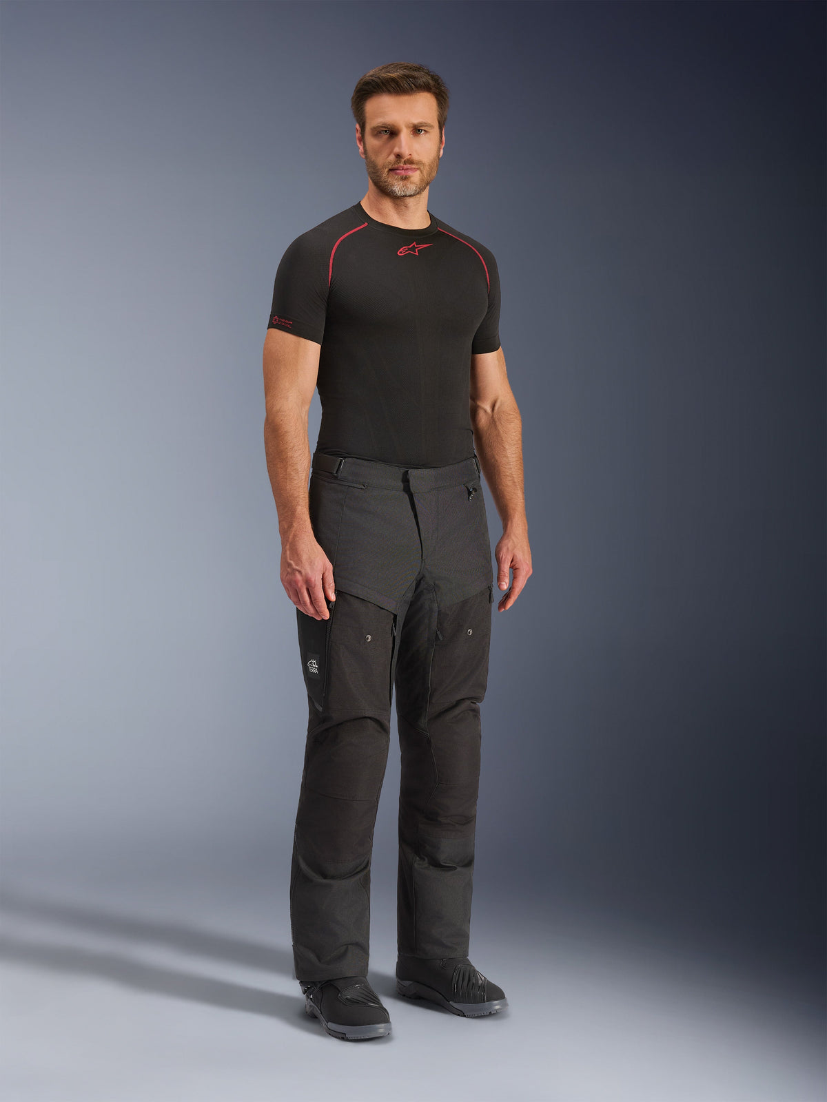 Alpinestars Cusco Drystar® bukser, sorte tekstil-motorcykelbukser, båret af en model med sort basislag og støvler, med ripstop-stof, store cargo-lommer med 'Terra'-branding og ergonomisk design til adventure-kørsel