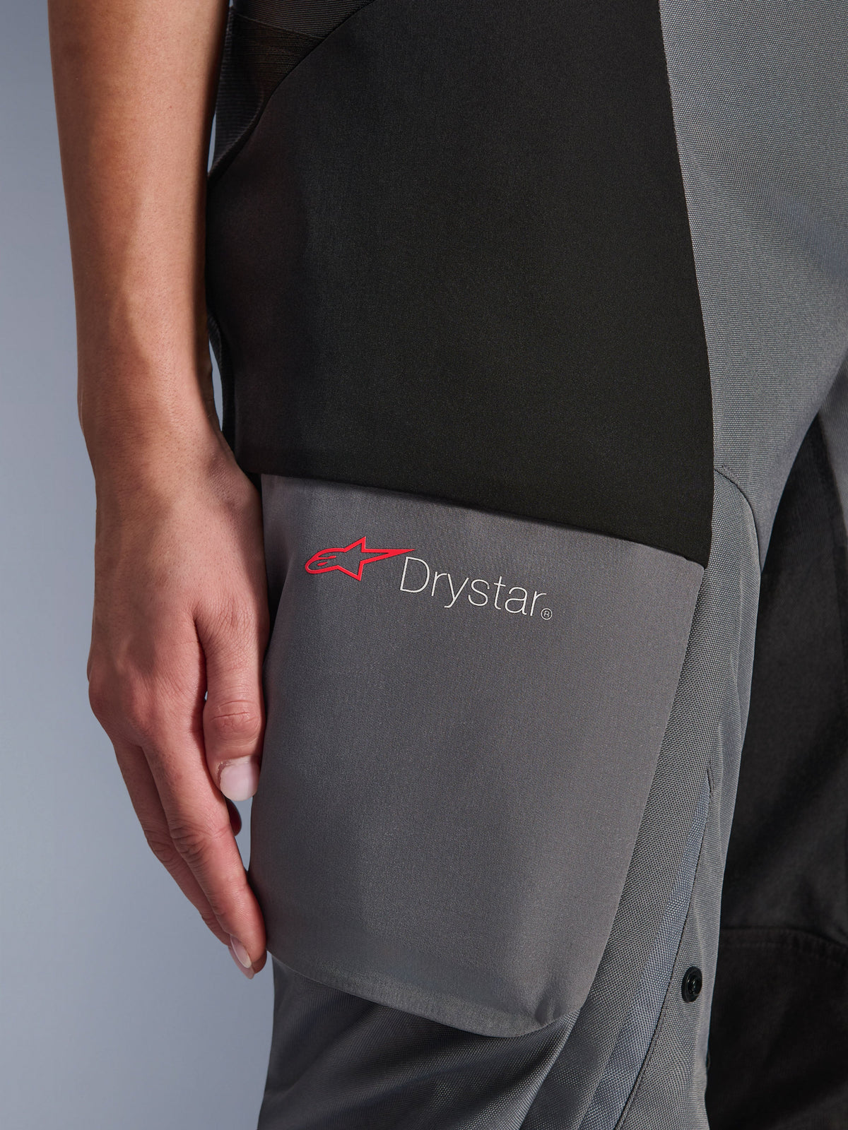 Alpinestars Stella Andes V4 Drystar® bukser, adventure-touringbukser til damer, sort og mørkegrå, detalje af lårområdet med Drystar-logo og rød Alpinestars-stjerne på forstærkede tekstilpaneler