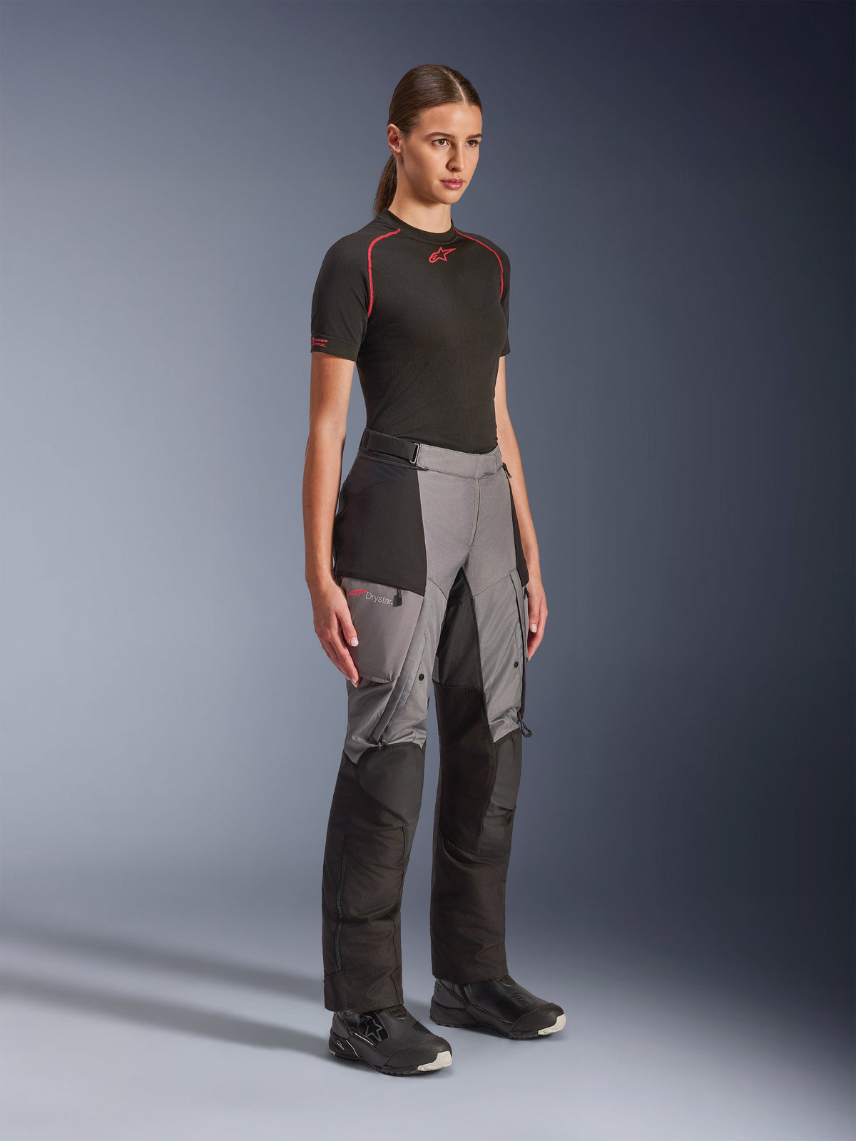 Alpinestars Stella Andes V4 Drystar® bukser, adventure-motorcykelbukser til kvinder, sort og mørkegrå, båret af en model med sort Alpinestars basislag og sorte støvler, med forstærkede paneler, rødt Drystar-logo og cargolommer.