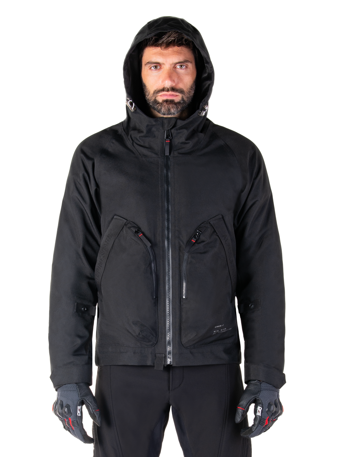 Alpinestars Morush Vandtæt Parka, urban motorcykeljakke til herrer, sort, vandtæt tekstil med stormsikker hætte og store frontlommer, båret af model med kørehandsker.