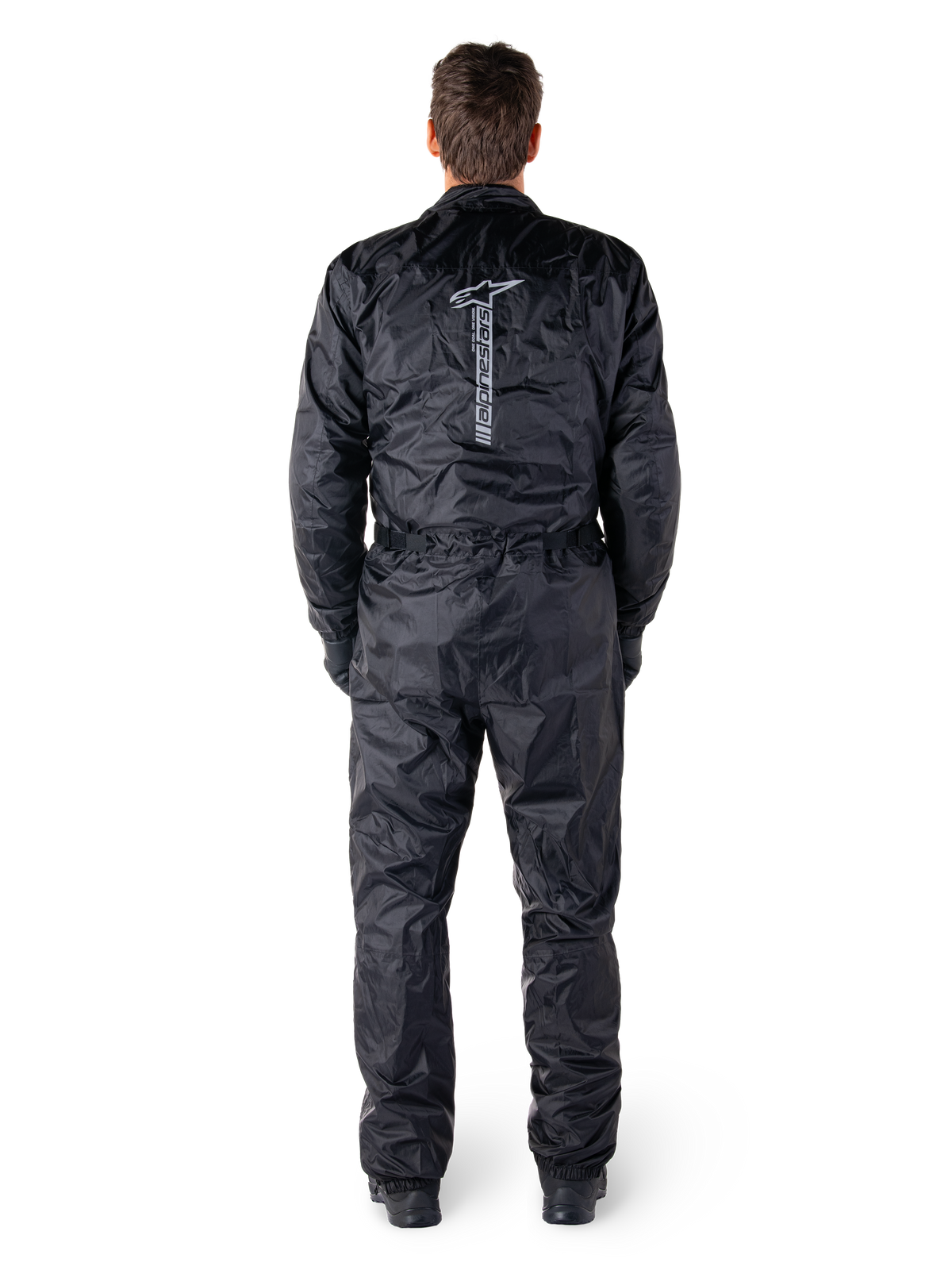 Alpinestars Hurricane Rain V2-dragt, sort vandtæt motorcykelheldragt, set bagfra med stort lodret Alpinestars-ordmærke og logo, letvægtsmateriale med krøleffekt, elastik i talje og manchetter, designet til beskyttelse under kørsel i vådt vejr.