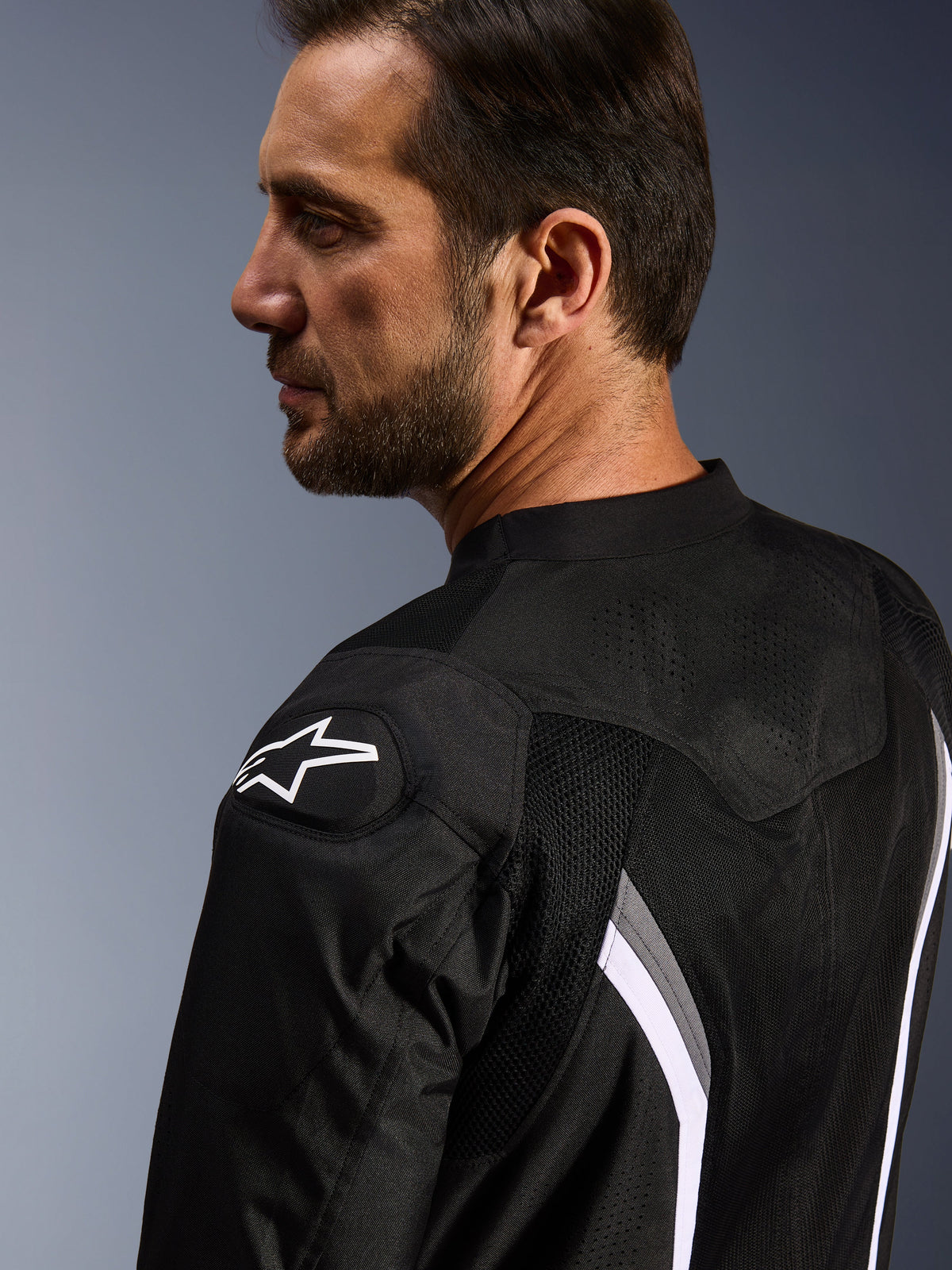 Alpinestars AST V3 Air jakke, motorcykeljakke, sort, mørkegrå og hvid, nærbillede bagfra, der viser hvidt stjernelogo på skulderen og laserperforerede mesh-paneler til ventilation.