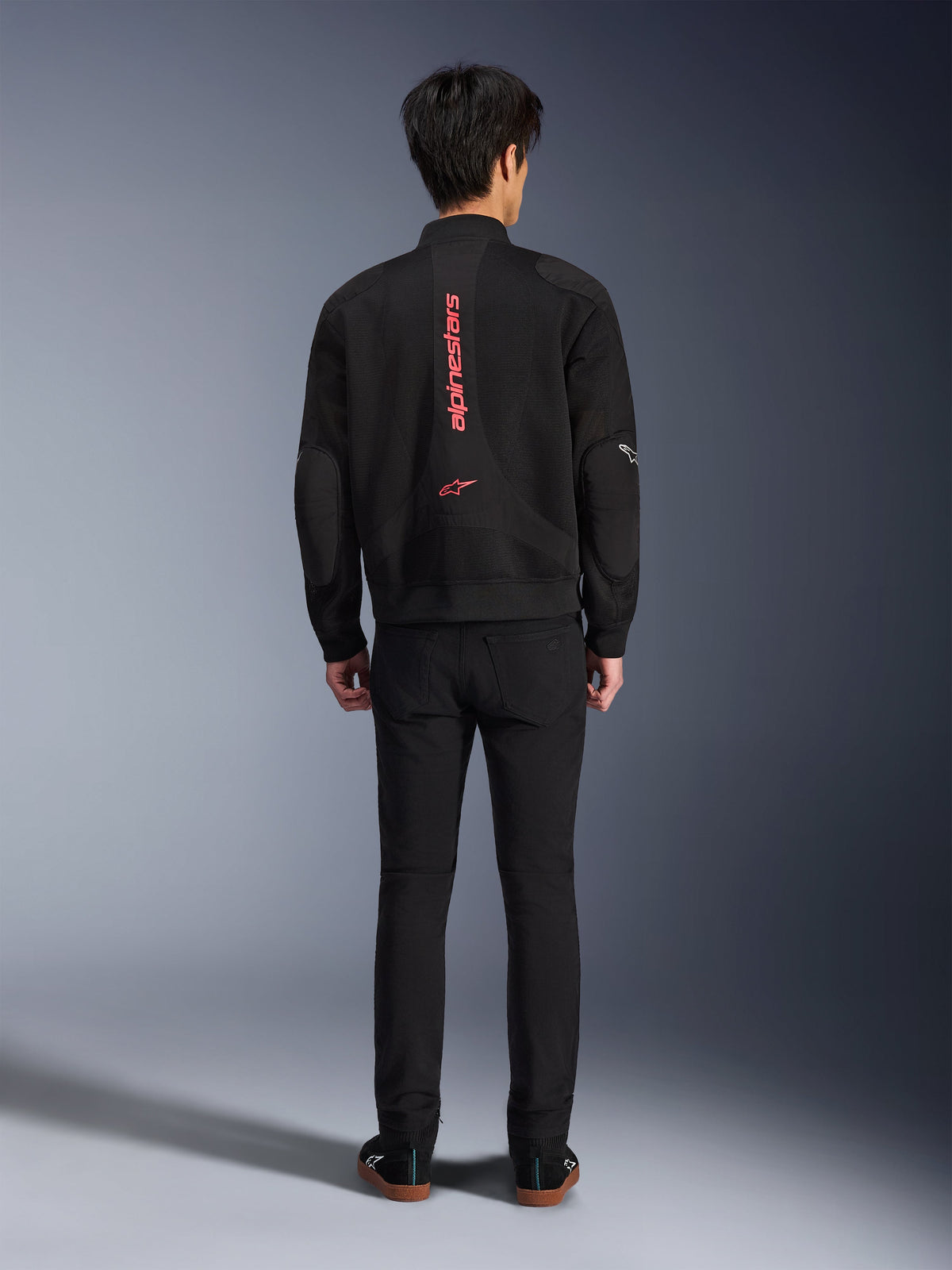Alpinestars Flight Air-jakke i sort og klar rød, urban motorcykeljakke i bomber-stil set bagfra, med lodret rød Alpinestars-branding og logo på ryggen, letvægts 3D-mesh-konstruktion, båret med sorte bukser for et moderne look.