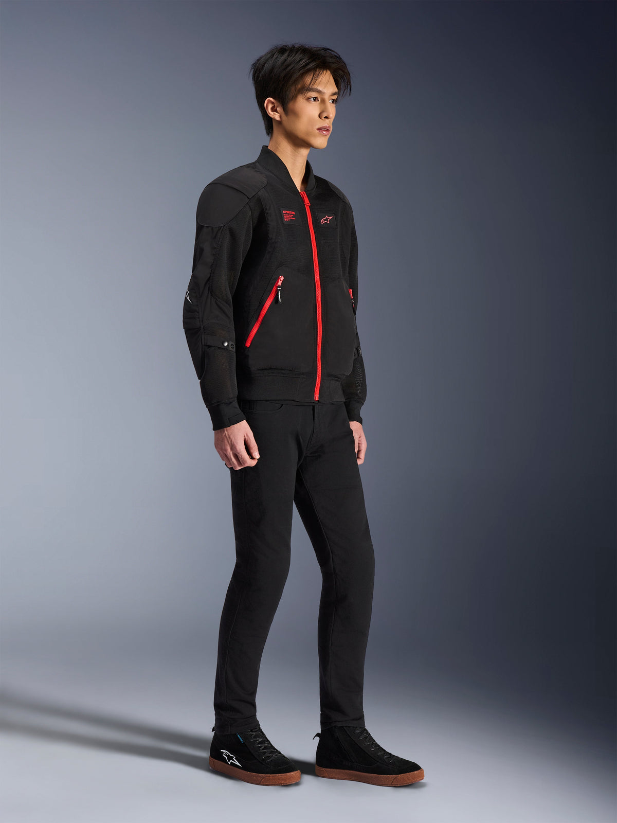 Alpinestars Flight Air Jacket, Black Bright Red, urban motorcykeljakke i bomber-stil båret af en model, med 3D mesh-paneler og kontrasterende røde lynlåse, kombineret med sorte bukser og afslappede kørselssko, moderne gadeinspireret beskyttelsesudstyr