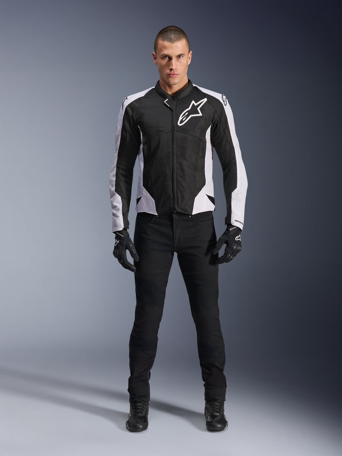 Alpinestars Viper Air V4 Jakke, sort og hvid motorcykeljakke med stort hvidt logo på brystet, båret af en mandlig model med sorte bukser og handsker, med mesh-paneler til ventilation, sporty beklædning til landevejskørsel