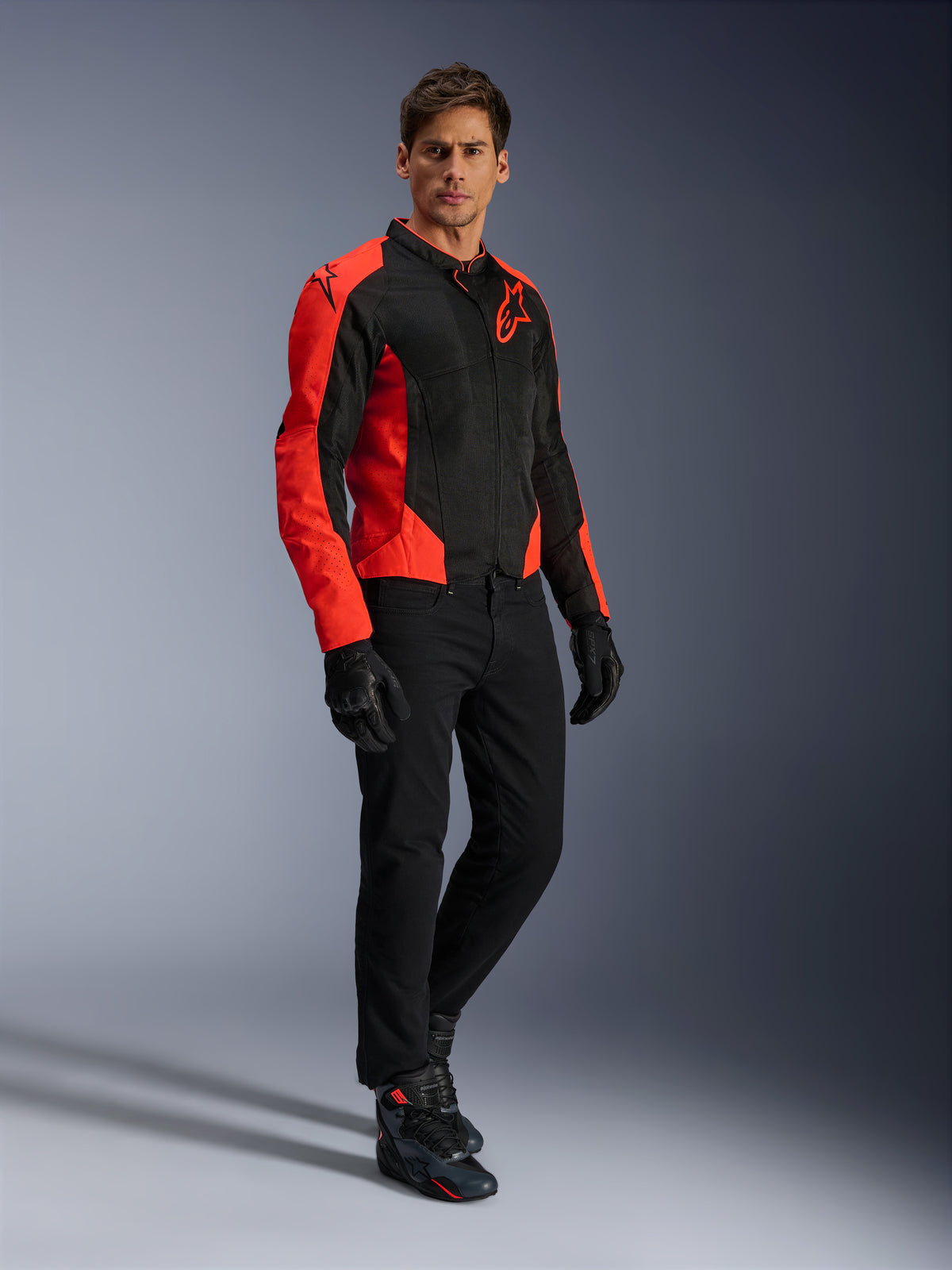 Alpinestars Viper Air V4-jakke, motorcykeljakke, rød fluo og sort, båret af model med sorte kørejeans, sorte handsker og motorcykelsko, tekstil-mesh-design med markante røde paneler og stjernelogo, sportsligt køreudstyr til landevejen