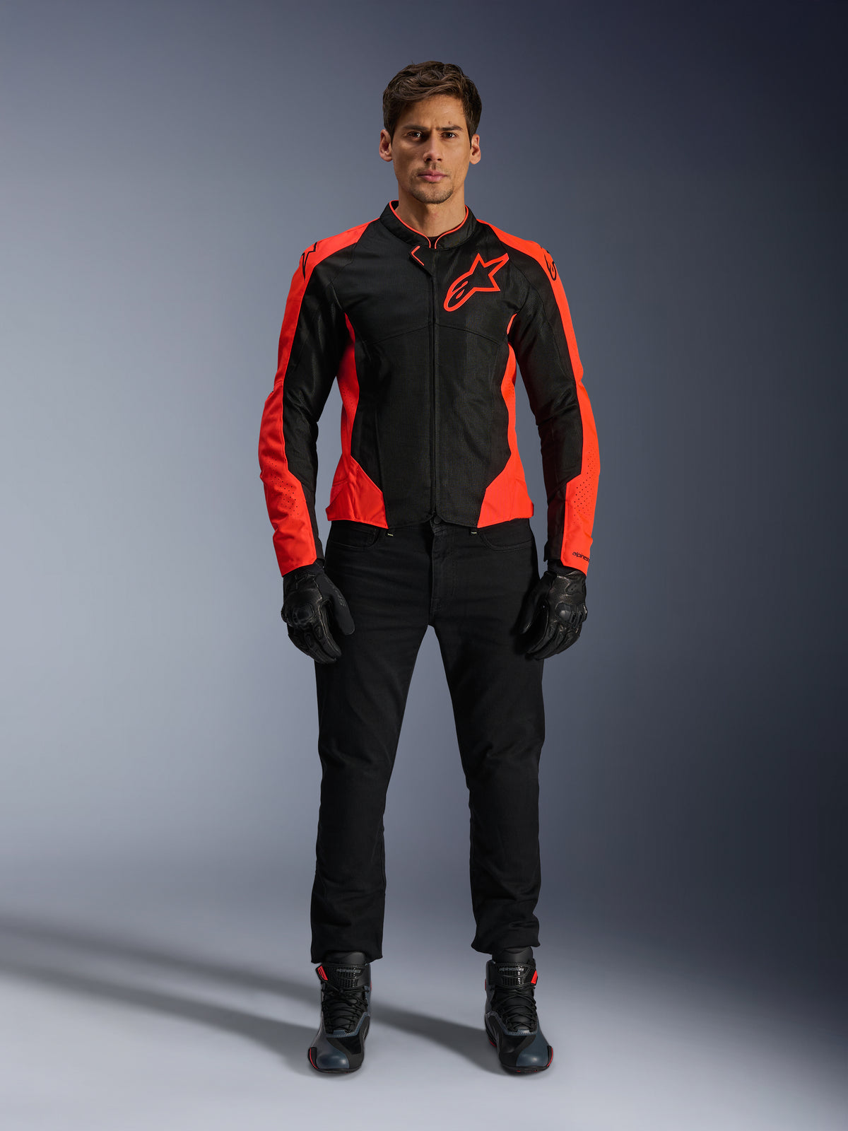 Mandlig model iført Alpinestars Viper Air V4-jakke i Red Fluo og sort, kombineret med sorte kørebukser, handsker og støvler, med åndbare mesh-paneler til ventilation og et markant stjernelogo på brystet, sportsligt motorcykeludstyr til vejbrug