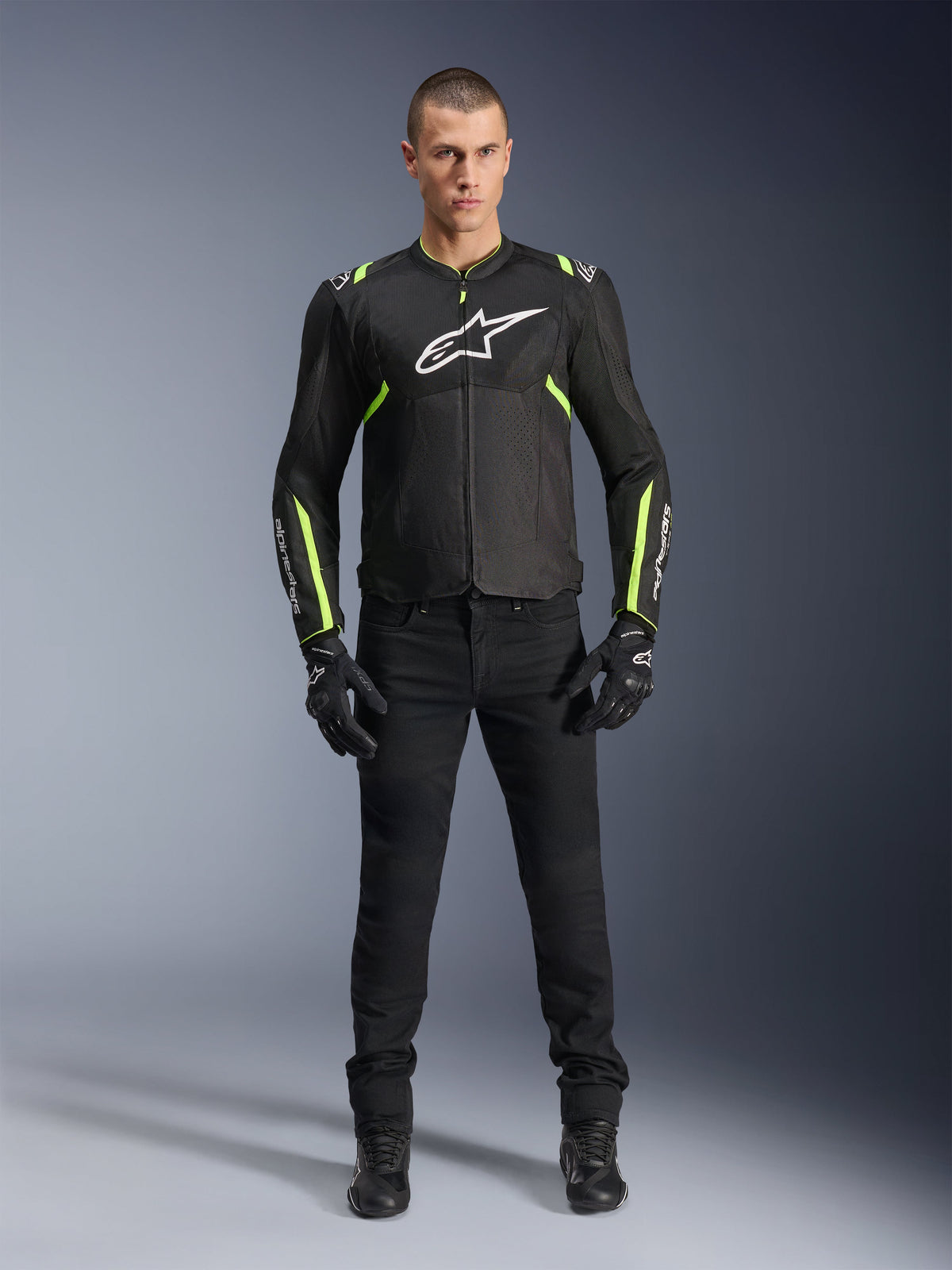 Alpinestars T-Sps Air V2 Jakke, Sort og Gul Fluo, tekstil motorcykeljakke med mesh-paneler, båret af mandlig model med sorte bukser og handsker, med hvidt Alpinestars-logo på brystet, urban sport-køreudstyr