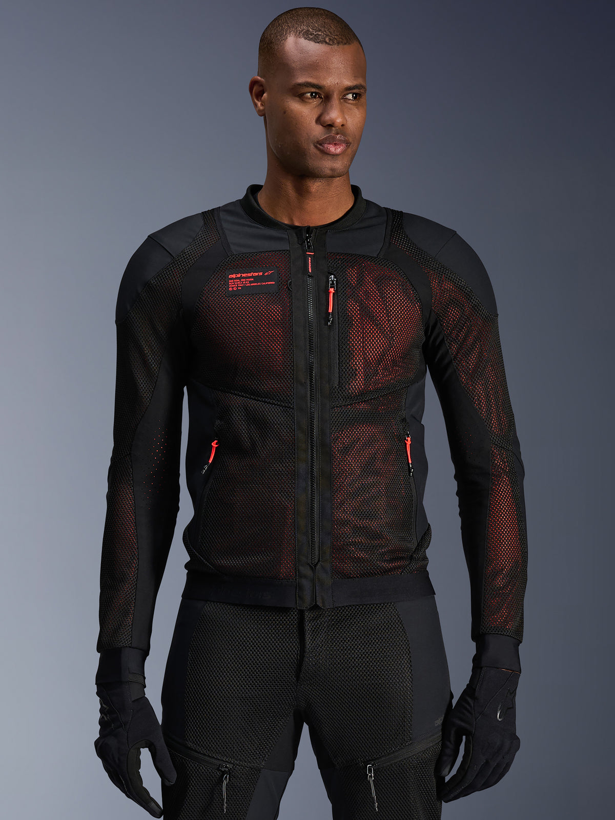 Alpinestars Troop-Air Pro Jakke, teknisk pansret motorcykeljakke, sort og fluorød, med røde lynlåstrækkere og Alpinestars-logo, åndbare mesh-paneler med rødt underlag, båret med matchende sorte kørebukser og handsker
