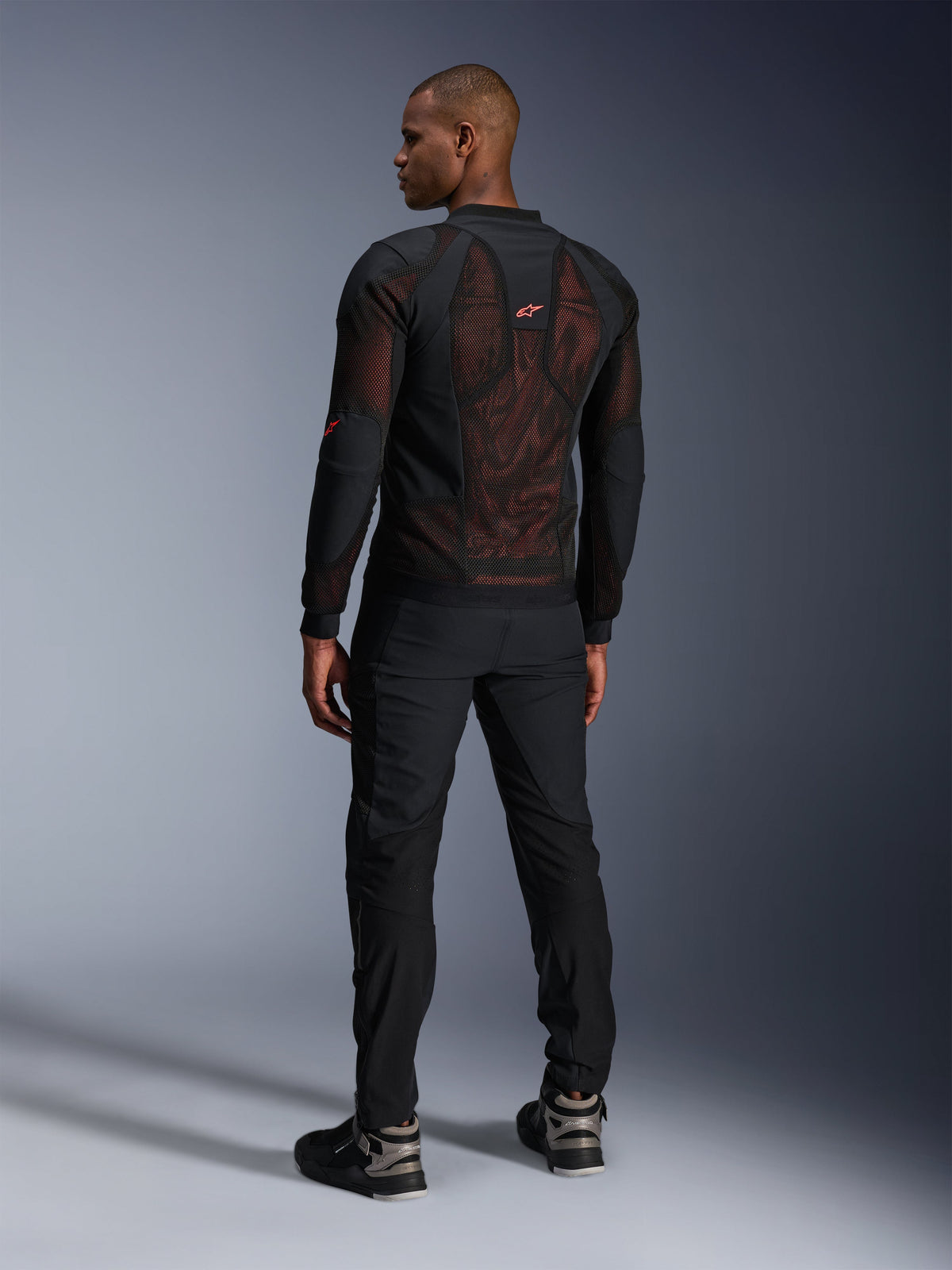 Alpinestars Troop-Air Pro Jakke i Sort Rød Fluo, set bagfra på en model, med stort 2D tech mesh-rygpanel og synligt rødt interiør, kombineret med sorte tekniske motorcykelbukser og sort-grå støvler, moderne urbant beskyttelsesudstyr til motorcykel