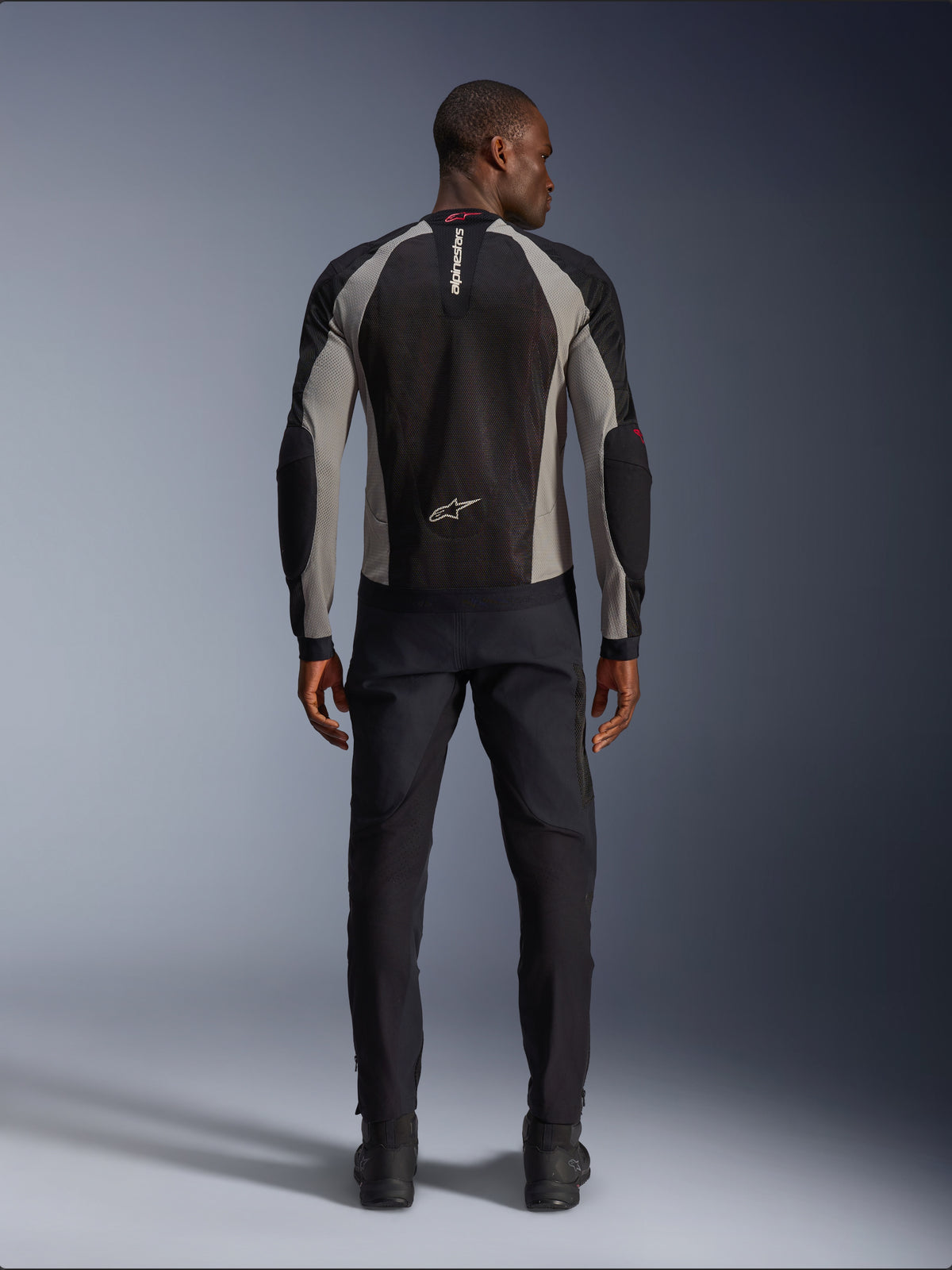 Alpinestars Troop-Air jakke, motorcykeljakke i sort, askegrå og klar rød, set bagfra på mandlig model, letvægts mesh-konstruktion til ventilation, Alpinestars-branding på krave og nederste del af ryggen, kombineret med sorte motorcykelbukser