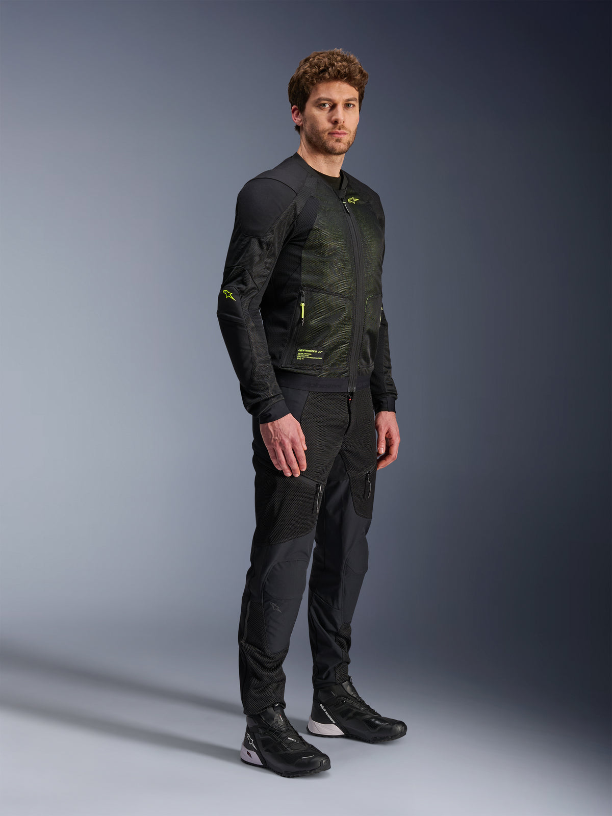 Alpinestars Troop-Air jakke, motorcykel mesh-jakke, sort og gul fluo, bæres af en model med matchende sorte bukser og køresko, high-airflow mesh-konstruktion med gule fluorescerende detaljer på brystet og ærmerne, letvægts teknisk design til landevejskørsel