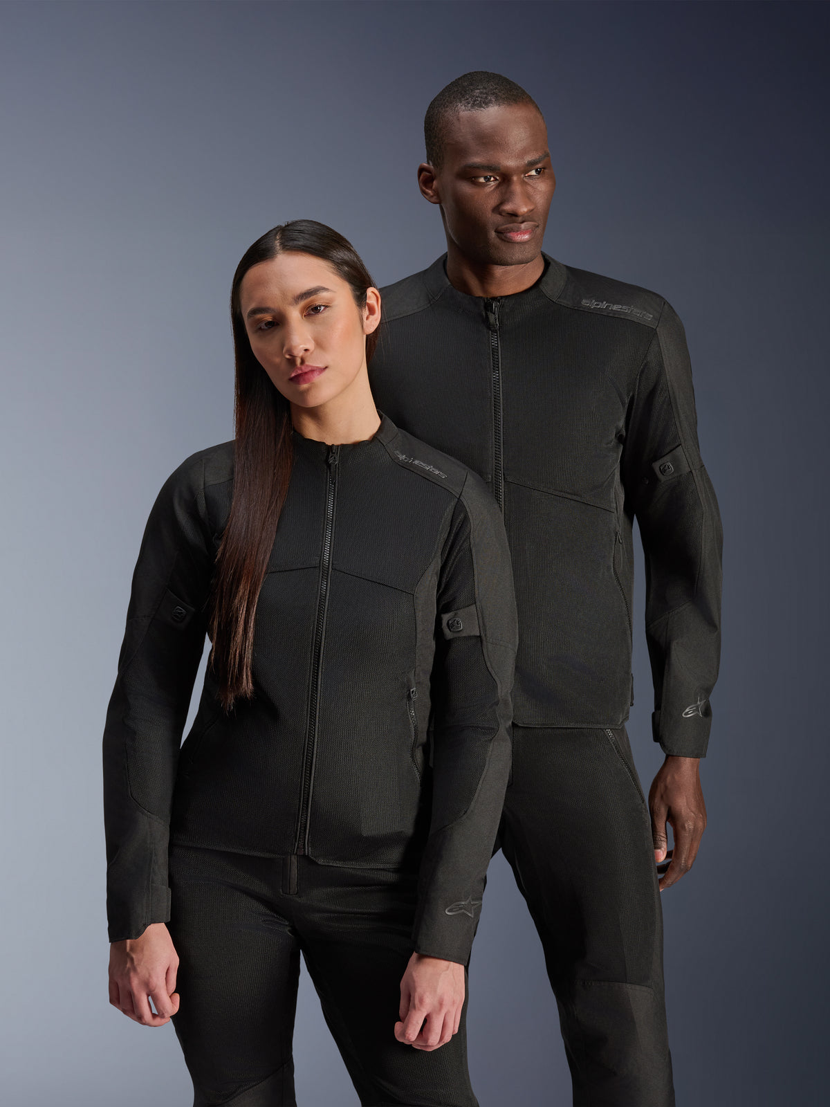 Alpinestars Stella C-1 Air-jakke, sort, båret af en mandlig og en kvindelig model, teknisk mesh-konstruktion for luftgennemstrømning, reflekterende logoer, strømlinet urbant motorcykeludstyr