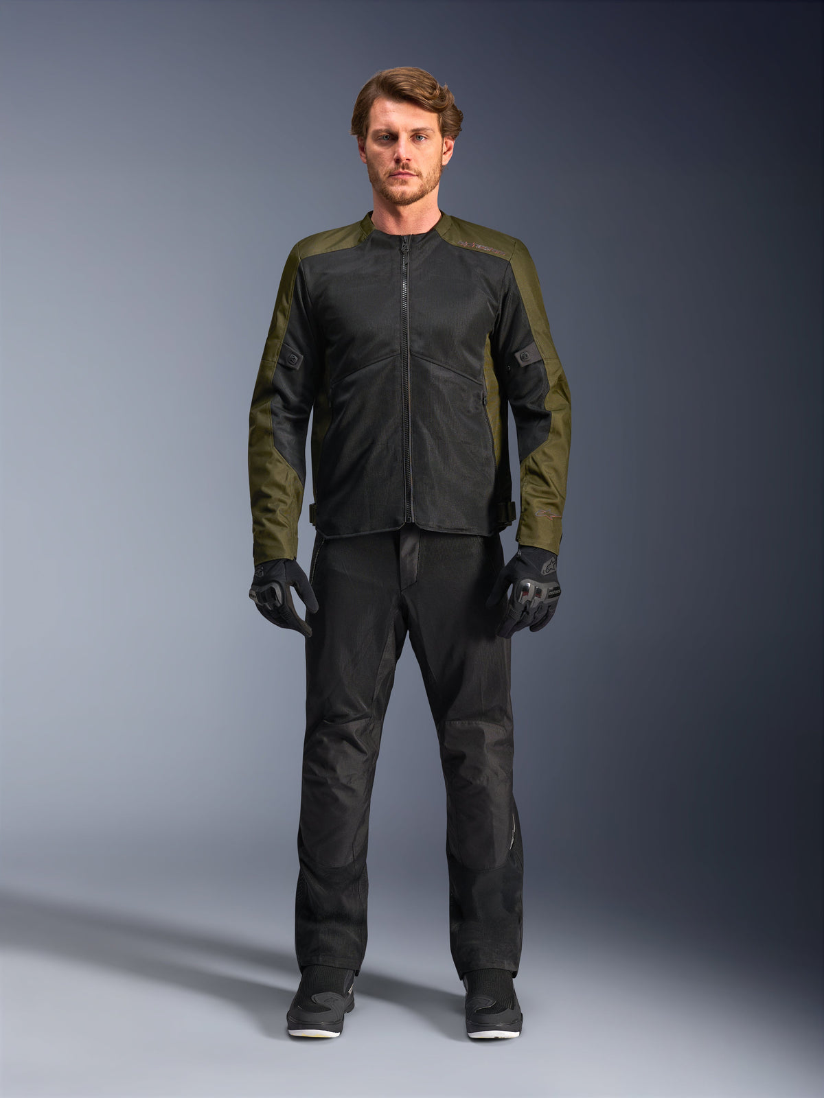 Alpinestars C-1 Air-jakke, khaki og sort, båret af mandlig model med sorte motorcykelbukser og handsker, letvægts tekstildesign med tech mesh-paneler, moderne urbant køreudstyr