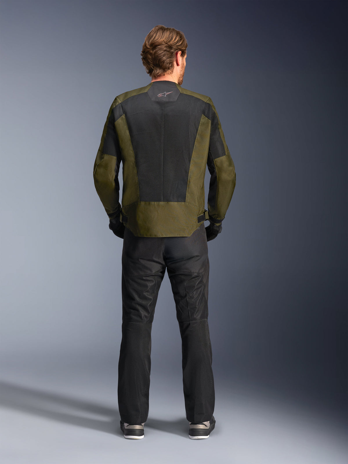 Alpinestars C-1 Air-jakke i khaki og sort set bagfra, med et stort tech mesh-rygpanel til ventilation, kombineret med sorte motorcykelbukser, moderne urbant motorcykeludstyr til vejbrug