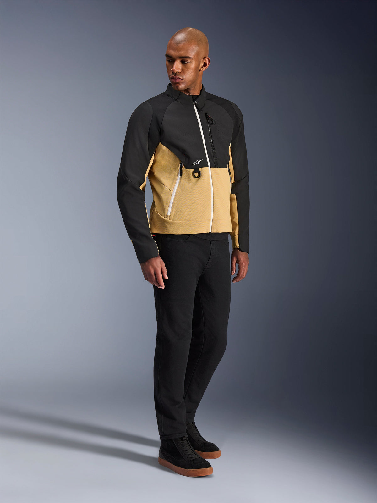 Alpinestars Provoke Jakke, urban motorcykeljakke, Black Camel, båret af en model med sorte bukser og sneakers, tofarvet tekstildesign med sort overdel og camel-farvet underdel, hvide lynlåsdetaljer, moderne urbant køreudstyr
