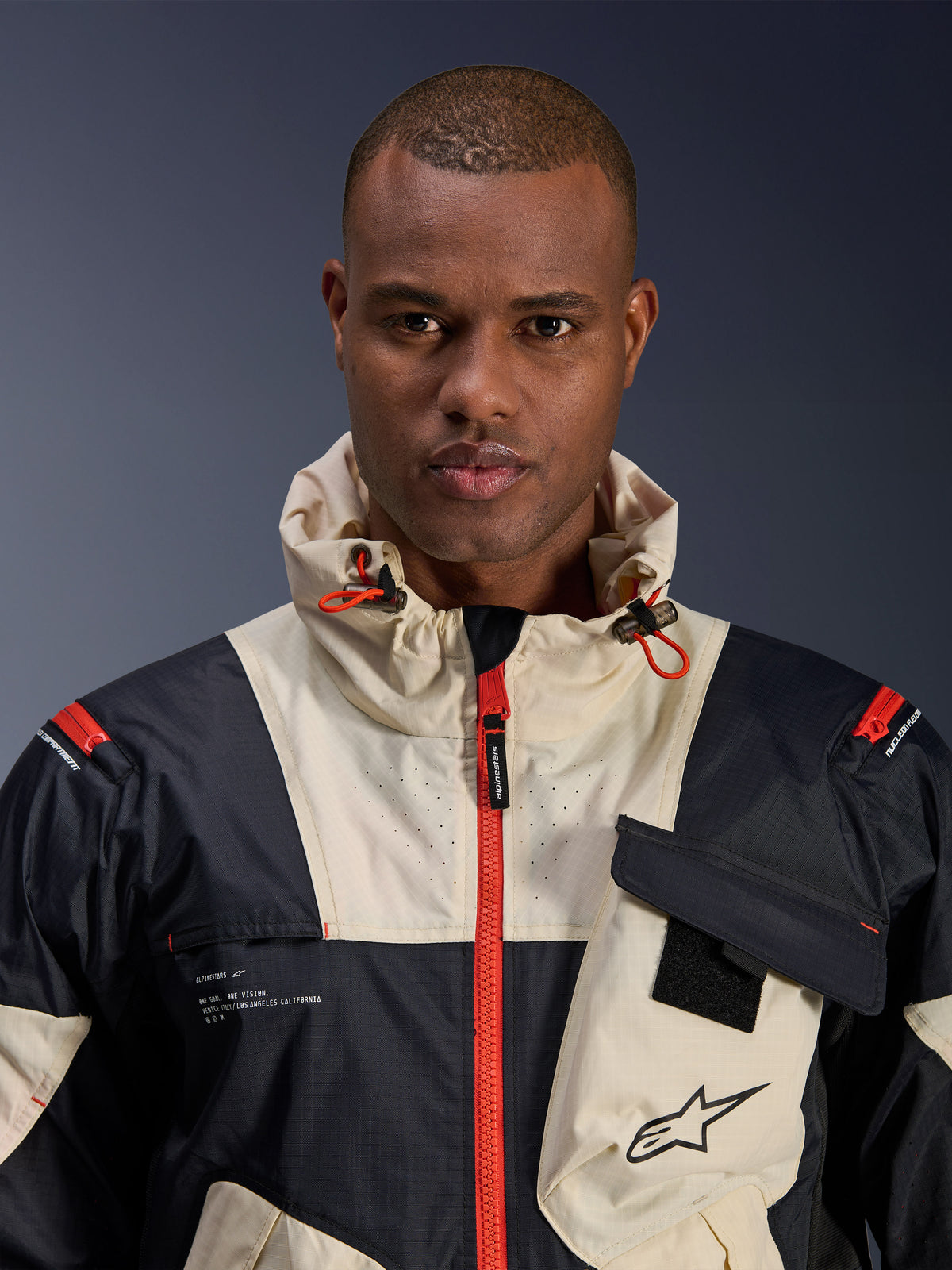 Alpinestars Mogress Air Jakke, herre-urban motorcykeljakke i sort og orange ripstop-tekstil med hætte.