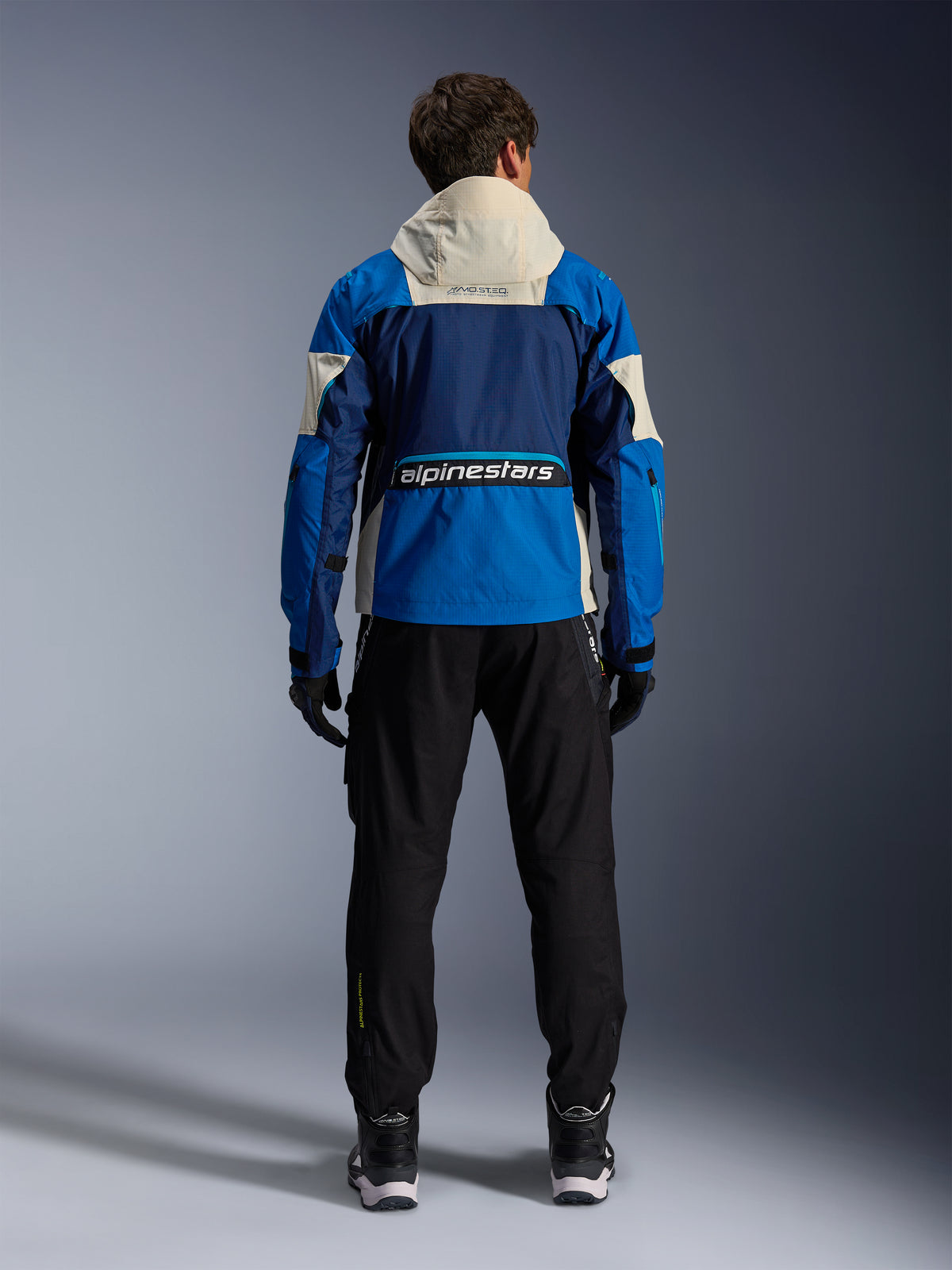 Alpinestars Mogress Air herre-motorcykeljakke i blå og almond, CE-certificeret ripstop, set bagfra med hætte og logo.