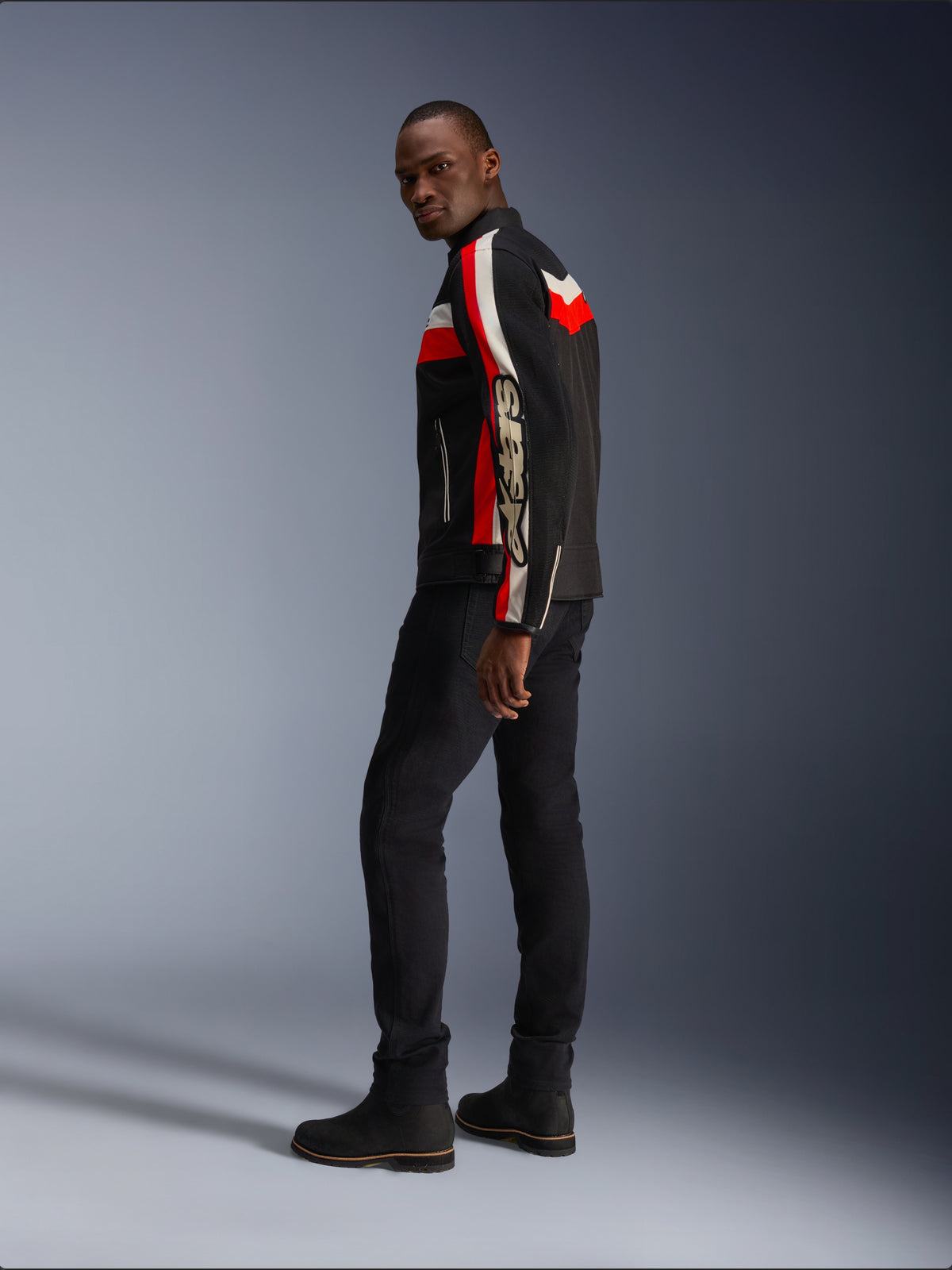 Alpinestars T-Dyno Air Jakke i sort, klar rød og ecru, vintage-inspireret tekstil motorcykeljakke med mesh-paneler, markant branding på ærmet, kombineret med sorte bukser og støvler for et moderne biker-look
