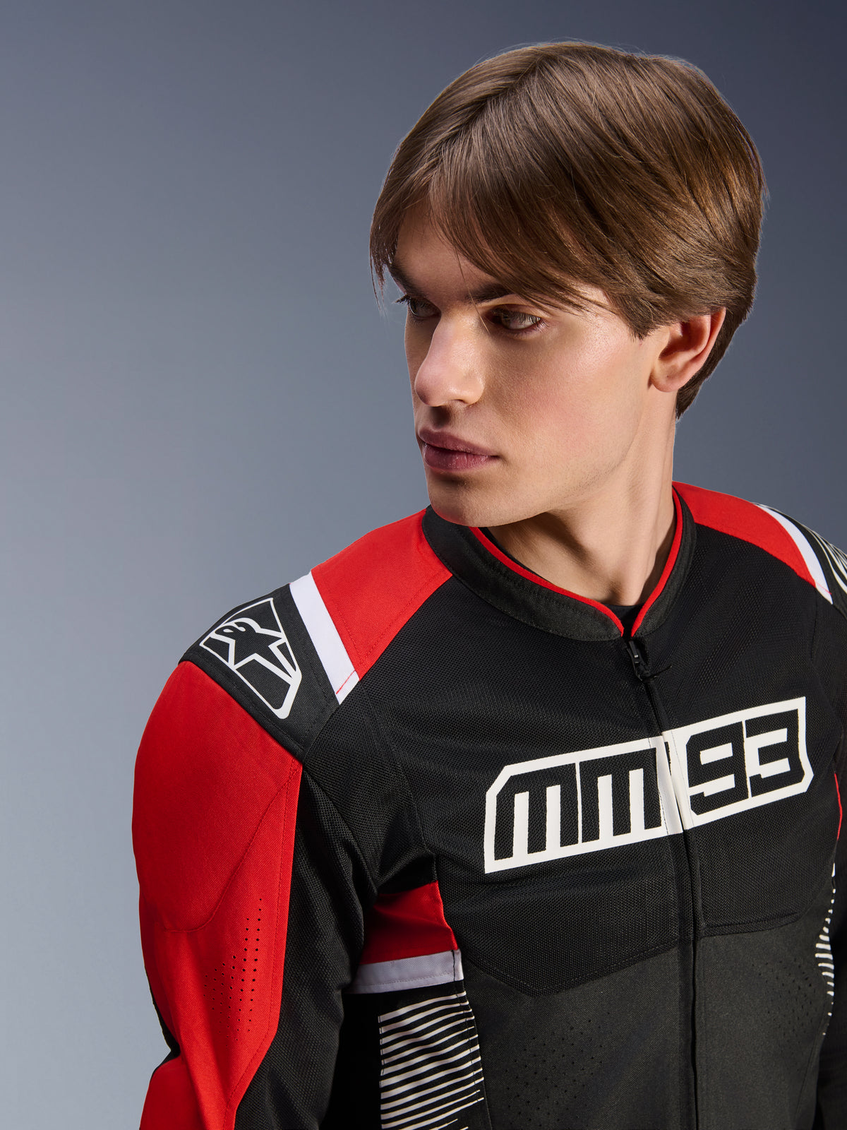Mandlig model iført Alpinestars MM93 T-SPS Air V2 jakke, tekstil motorcykeljakke, sort, klar rød og hvid, med markant MM 93-branding på brystet og stjernelogo på skulderen, mesh-konstruktion for luftgennemstrømning, sportsorienteret køreudstyr