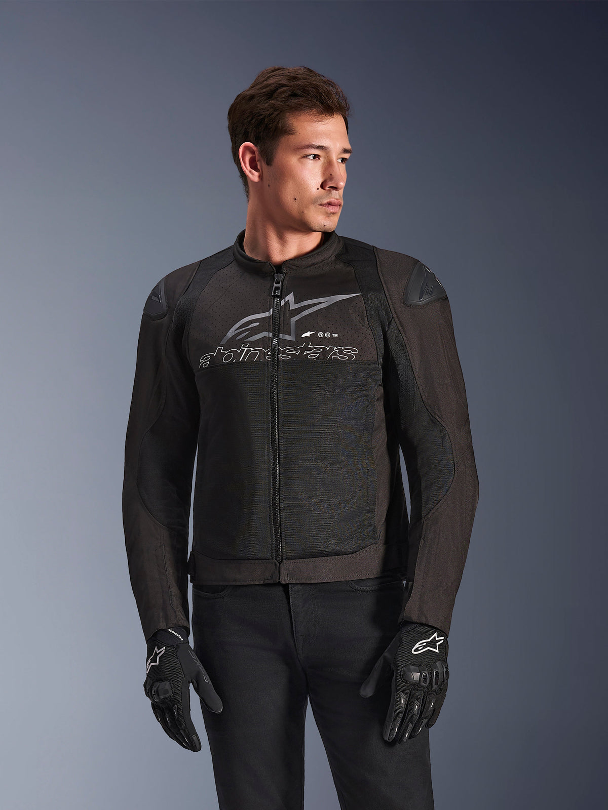 Alpinestars SMX Air Jacket in Black Anthracite, textile motorcycle jacket with high-flow mesh panels, features a large grey Alpinestars logo and text on the chest, DFS Lite shoulder sliders, worn by a model with black riding gloves, sport-riding style.