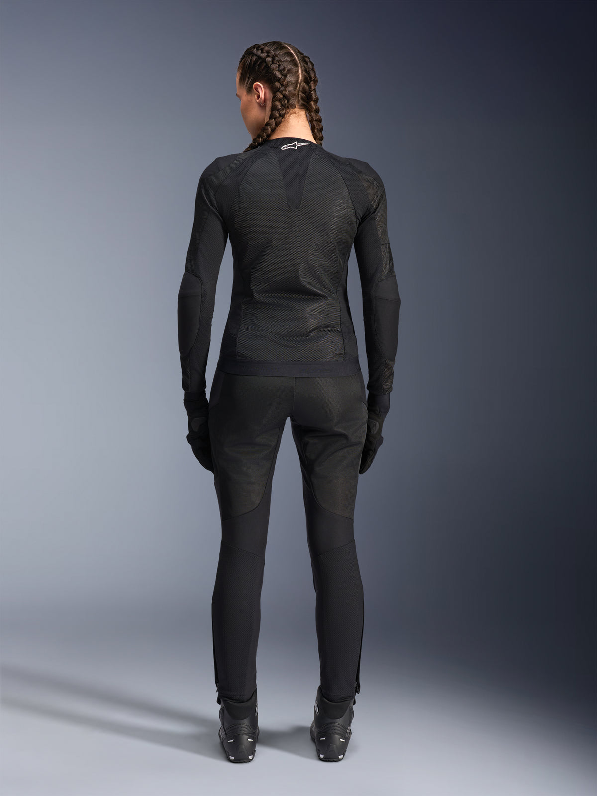 Alpinestars Stella Troop-Air jakke, dame motorcykeljakke, sort, set bagfra af en rytter iført en teknisk mesh-jakke, kombineret med matchende sorte kørebukser, handsker og støvler, tætsiddende åndbart design med et hvidt Alpinestars-logo på kraven