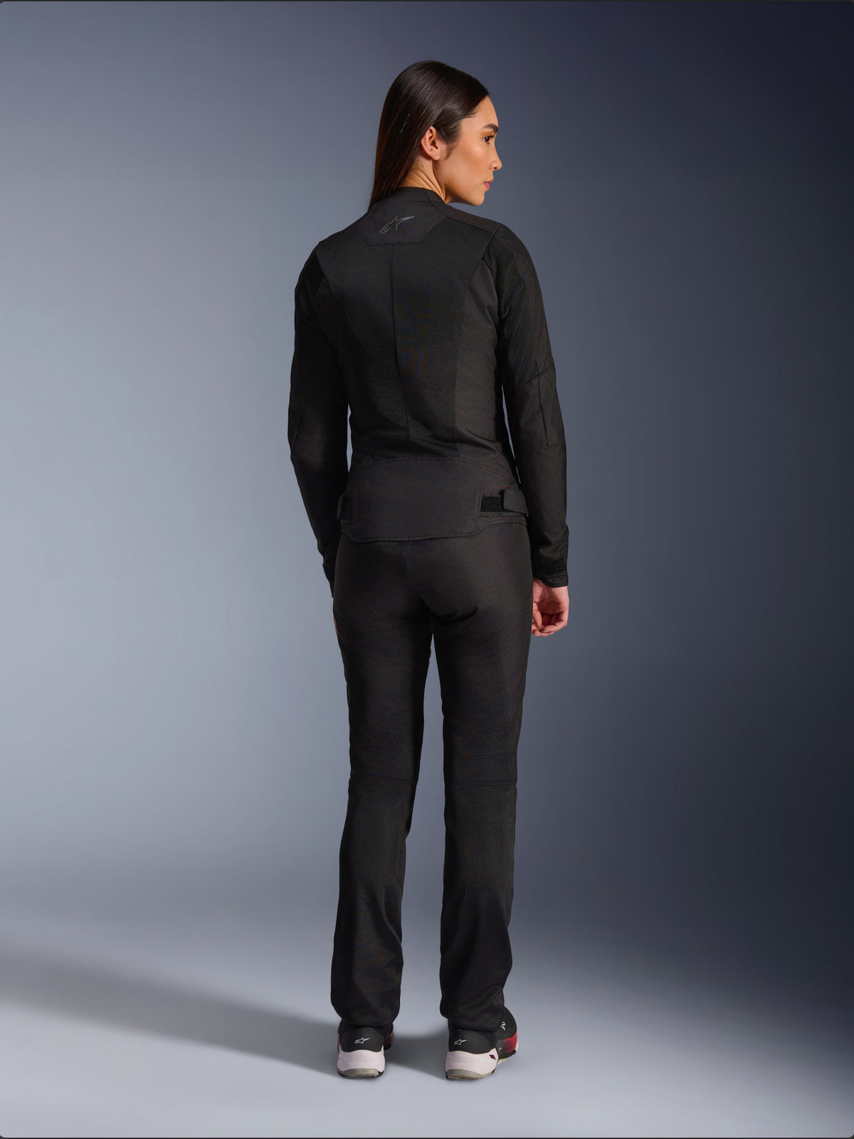 Alpinestars Stella C-1 Air jakke, tekstilmotorcykeljakke til damer, sort, set bagfra med mesh-konstruktion og diskret logo øverst på ryggen, båret med matchende sorte mc-bukser, moderne urban stil