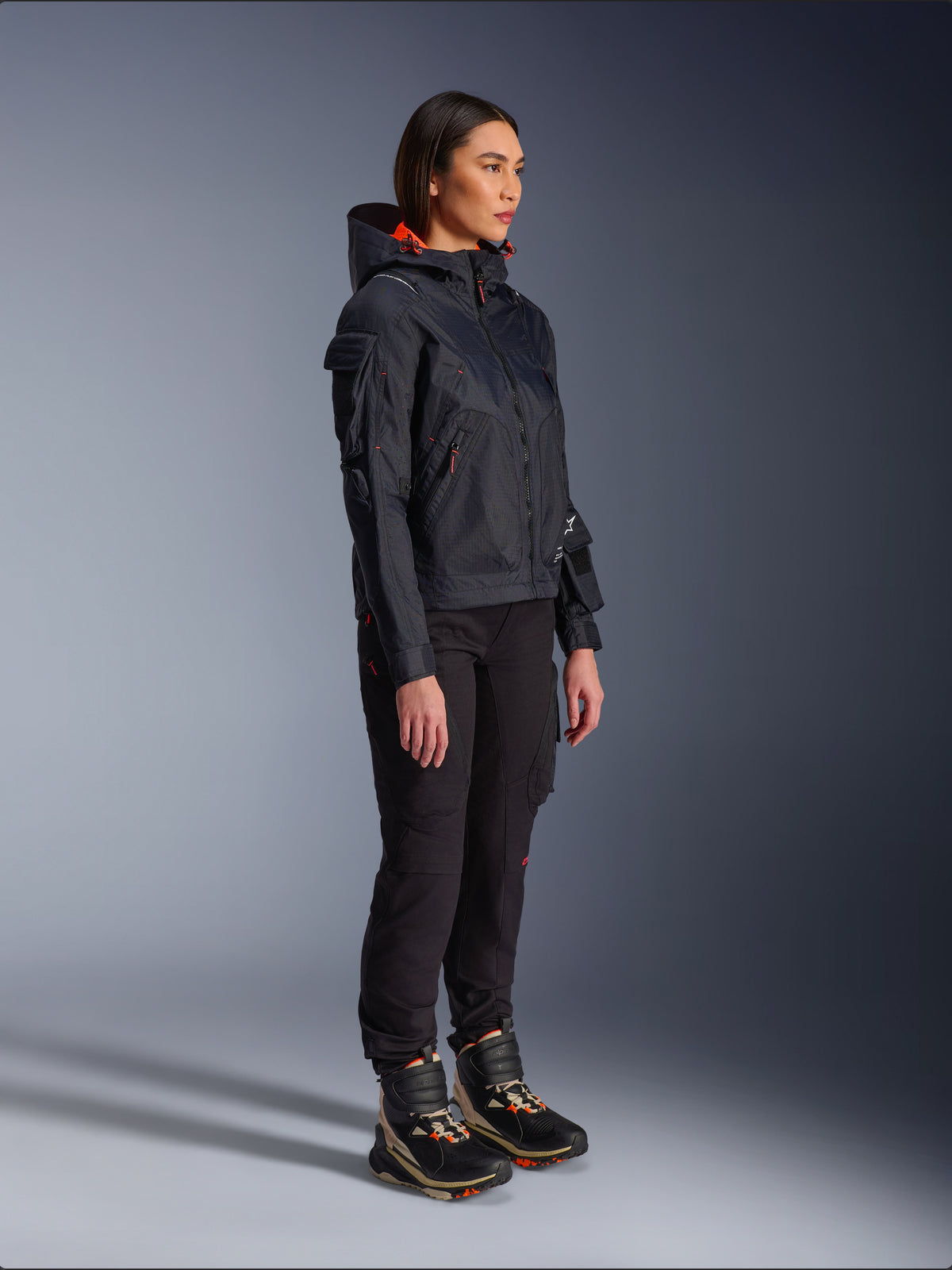 Alpinestars Actea Women's Pants in Black, regular fit with cargo pockets, styled with a black Molly Air Jacket with orange accents and high-top riding shoes, contemporary urban motorcycle apparel for women