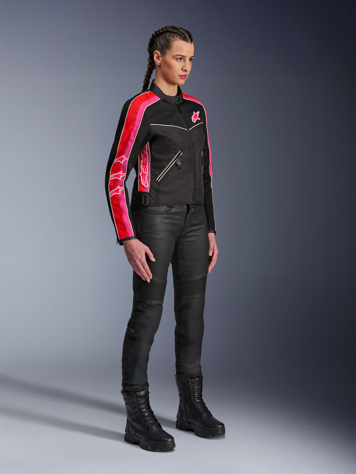 Alpinestars Stella T-Dyno Air-jakke, motorcykeljakke til kvinder, sort med stærke røde og fuchsia-farvede striber på ærmerne, båret med sorte kørebukser og støvler, vintage-inspireret mesh-design til urban kørsel