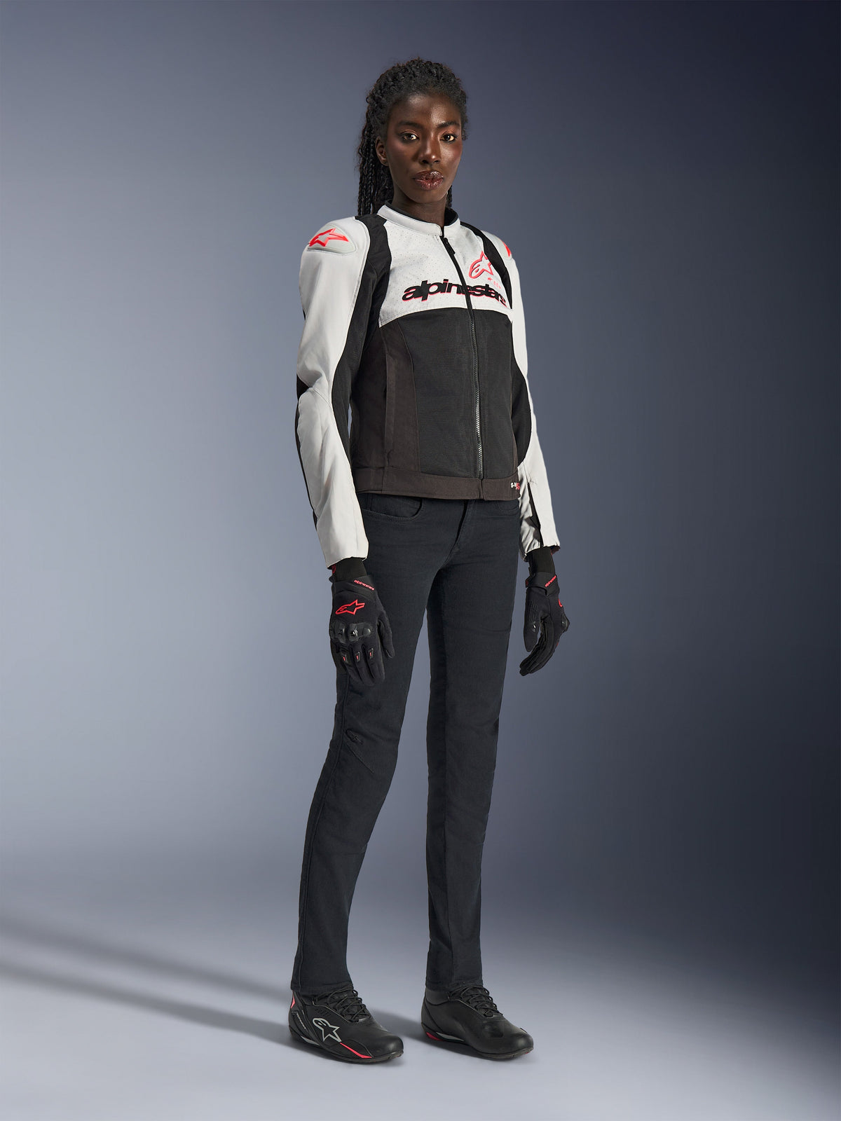 Alpinestars Stella SMX Air jakke til kvinder i Ice Gray Black Coral Fluo, båret af en kvindelig model med sorte motorcykelbukser og handsker, mesh-konstruktion og koralrøde logoer, sports-motorcykeludstyr til damer