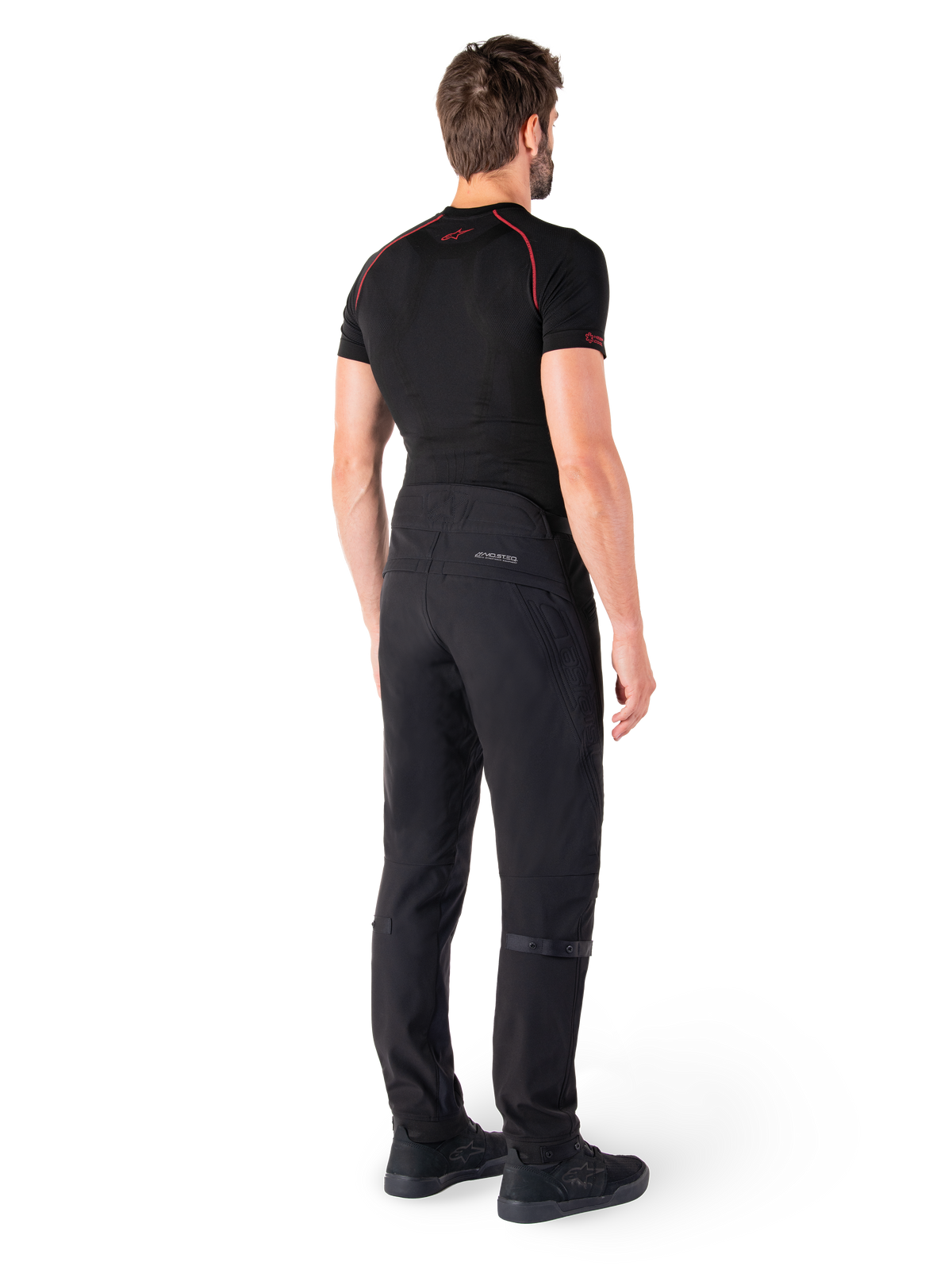 Alpinestars Alden Pants, Black, urban motorcycle pants shown from the back on a model, worn with a black short-sleeve base layer and black riding shoes, featuring quilted detailing and reflective MO.ST.EQ. branding on the back yoke.