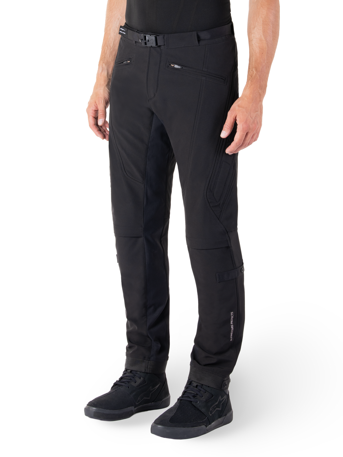 Alpinestars Alden Pants, Urban Motorcycle Pants, Black, technical softshell fabric with regular fit, featuring magnetic waist buckle, quilted side panels, zippered pockets, and subtle branding on the lower leg, worn with black riding shoes