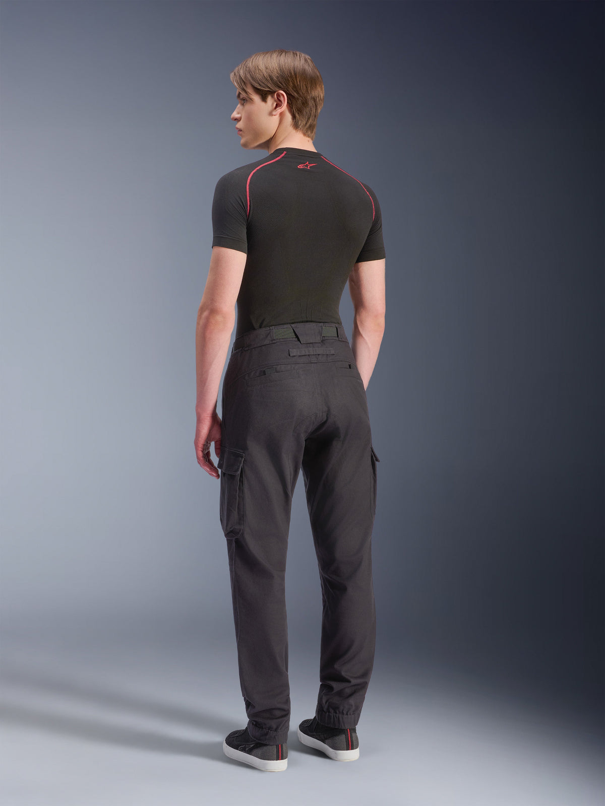 Alpinestars Flex-AST Cargo bukser - Short, motorcykel-cargobukser, sort, set bagfra af model i regular tapered pasform med sidelommer og elastiske opslag, kombineret med sort baselayer og fritidssko