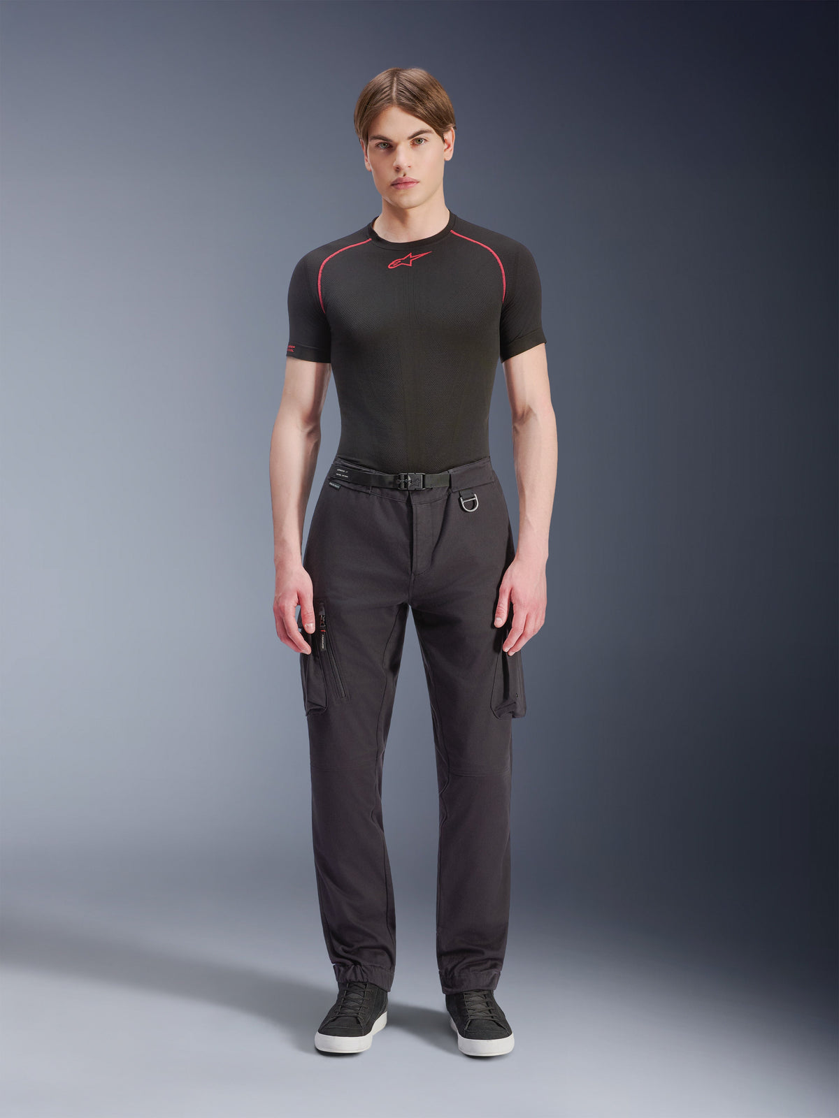 Alpinestars Flex-AST Cargo Pants - Short, sorte, båret af en mandlig model med en sort performance t-shirt og sorte sneakers, urbane motorcykelbukser med flere cargolommer, tilspidset pasform, indbygget bælte med spænde og D-ring